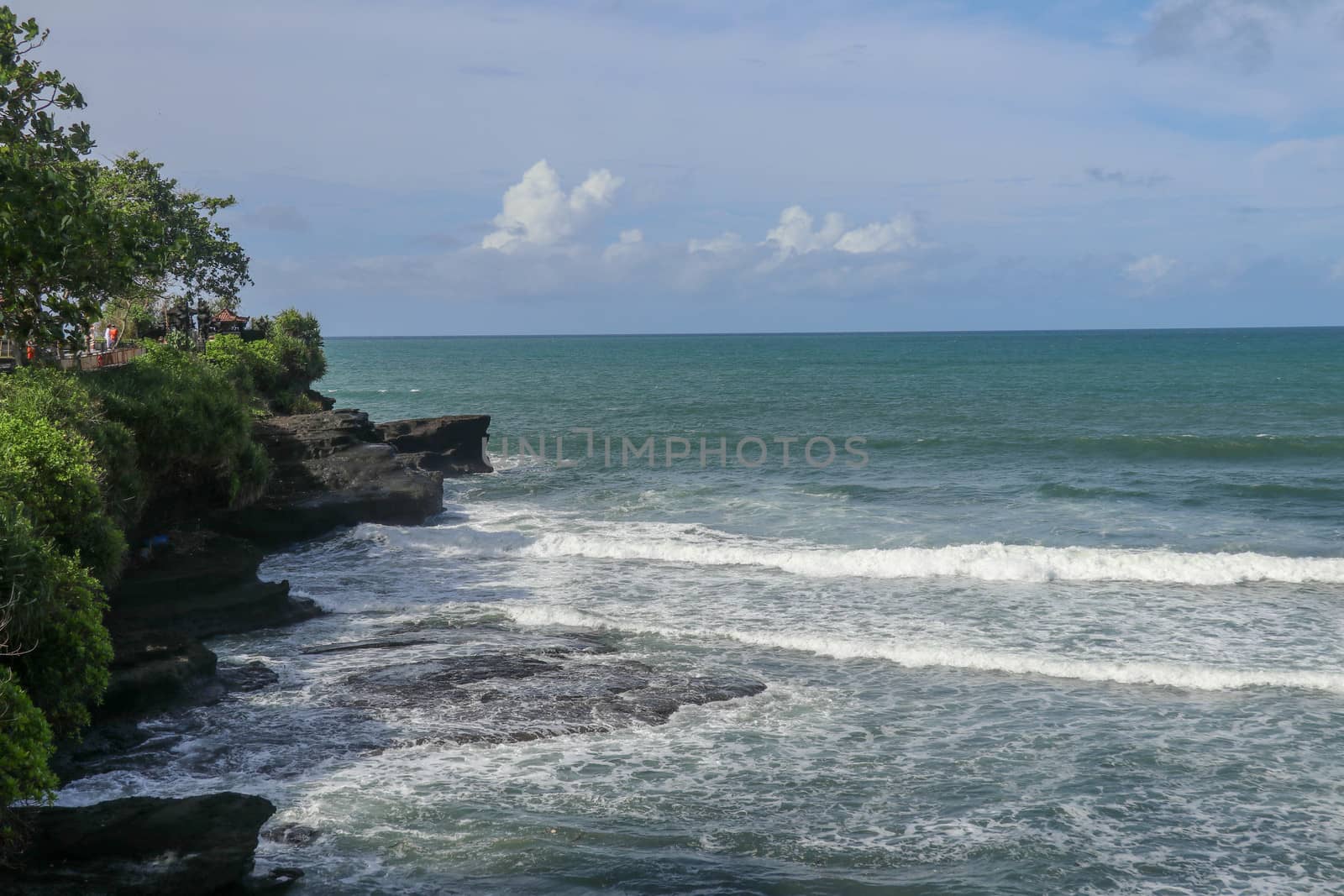 Indian Ocean coast near the Sacred Balinese temple Tanah Lot. Pura Batu Bolong on the edge of a cliff at coastline with hole in the rock. Holy place for local indonesian people