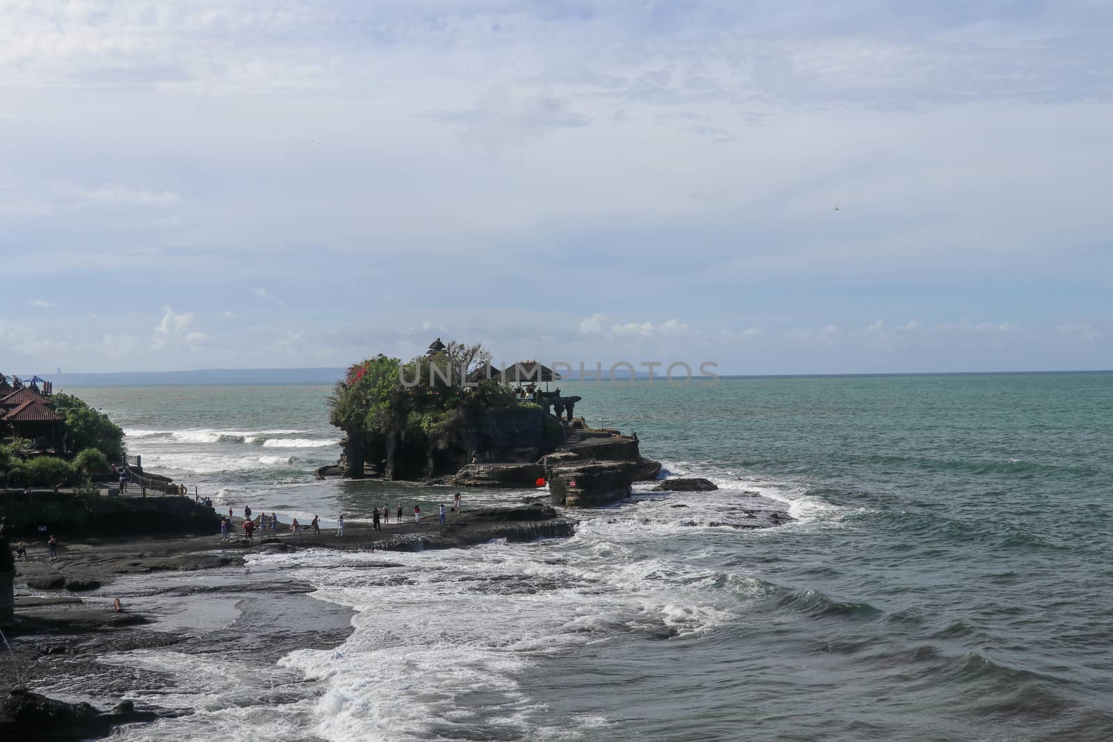 Indian Ocean coast near the Sacred Balinese temple Tanah Lot. Pura Batu Bolong on the edge of a cliff at coastline with hole in the rock. Holy place for local indonesian people