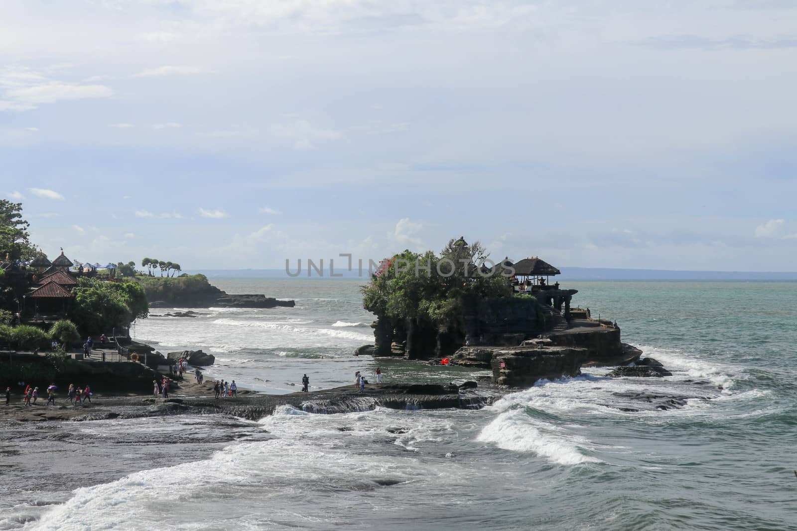 Indian Ocean coast near the Sacred Balinese temple Tanah Lot. Pura Batu Bolong on the edge of a cliff at coastline with hole in the rock. Holy place for local indonesian people