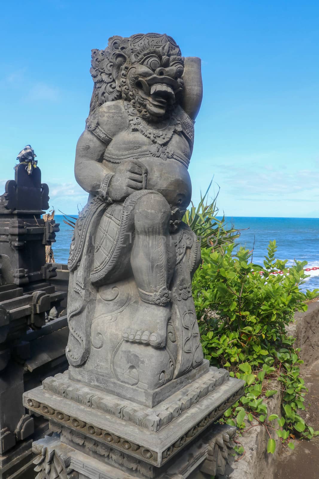 Closeup of stone statue in Temple Batu Bolong near to Tanah Lot in Bali, Indonesia. A carved statue with fine details that stands outside the entrance to Hindu temple as a guardian. Balinese culture.