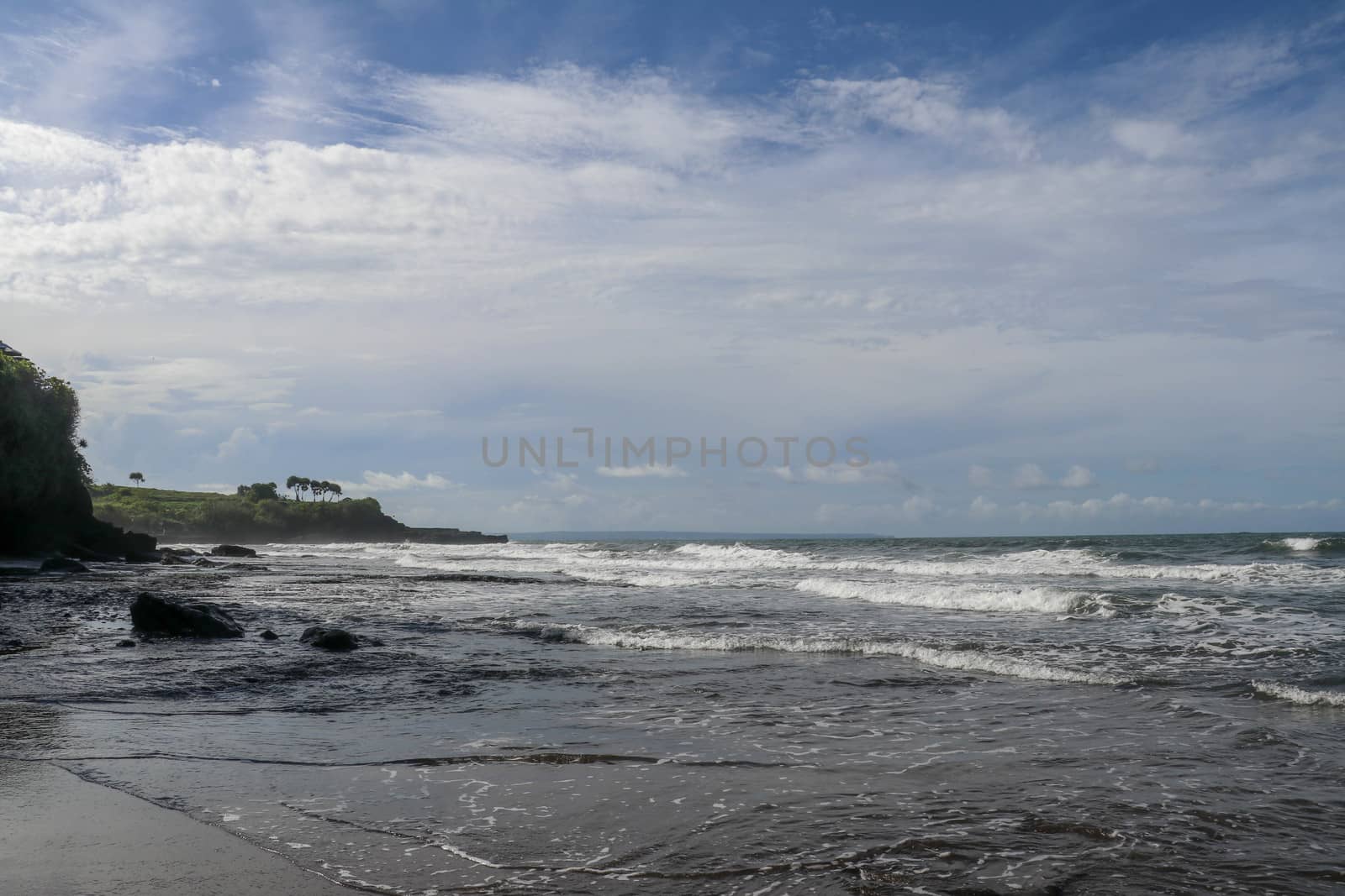 Indian Ocean coast near the Sacred Balinese temple Tanah Lot. Pura Batu Bolong on the edge of a cliff at coastline with hole in the rock. Holy place for local indonesian people