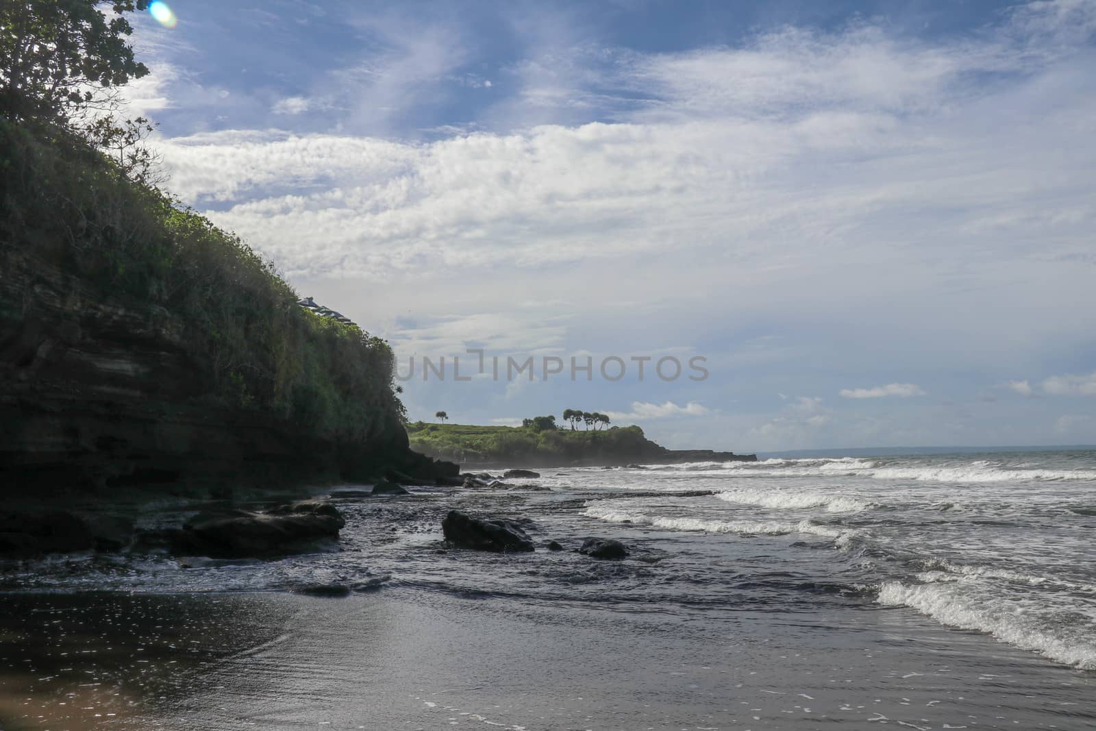 Indian Ocean coast near the Sacred Balinese temple Tanah Lot. Pura Batu Bolong on the edge of a cliff at coastline with hole in the rock. Holy place for local indonesian people