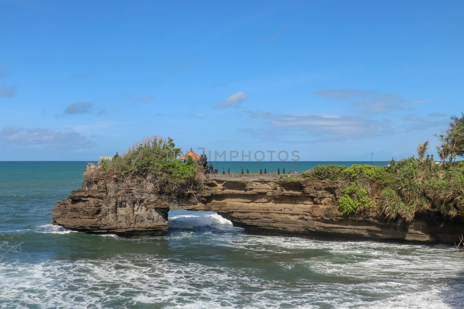 Indian Ocean coast near the Sacred Balinese temple Tanah Lot. Pura Batu Bolong on the edge of a cliff at coastline with hole in the rock. Holy place for local indonesian people