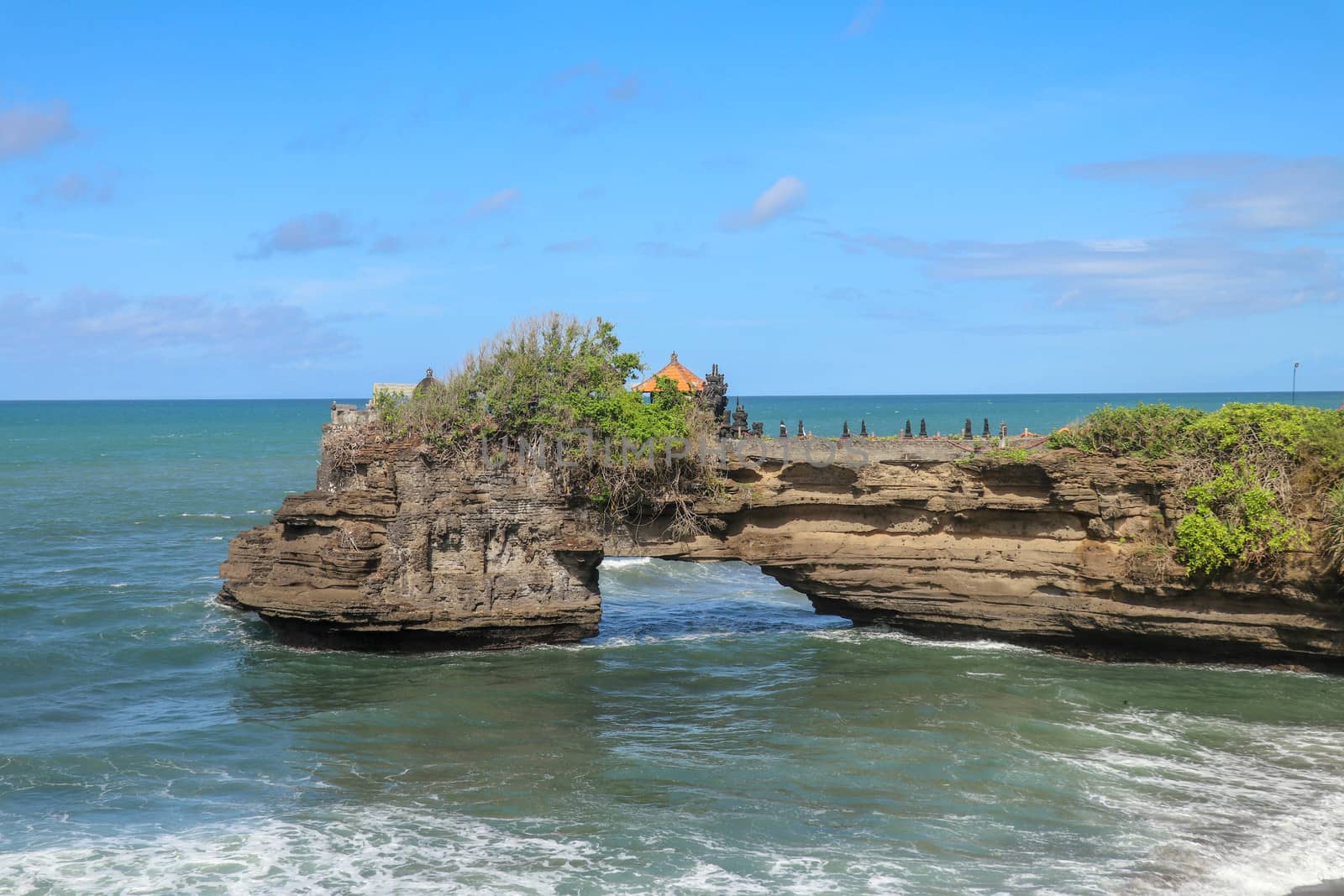 Indian Ocean coast near the Sacred Balinese temple Tanah Lot. Pura Batu Bolong on the edge of a cliff at coastline with hole in the rock. Holy place for local indonesian people