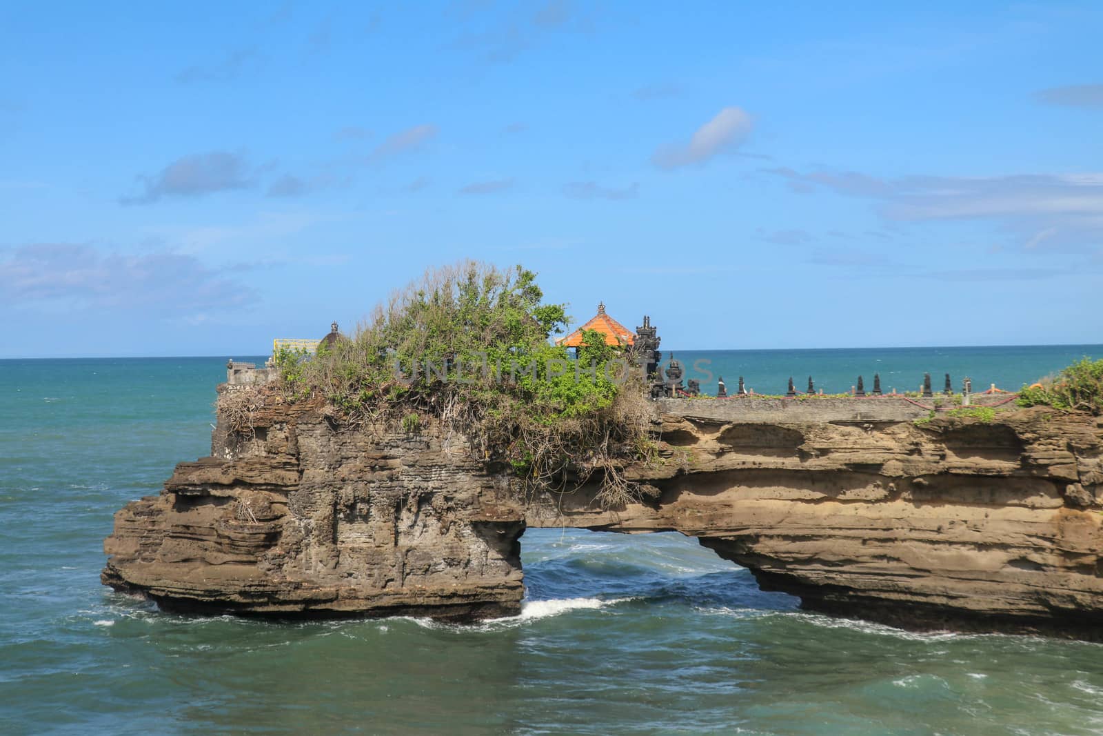 Indian Ocean coast near the Sacred Balinese temple Tanah Lot. Pura Batu Bolong on the edge of a cliff at coastline with hole in the rock. Holy place for local indonesian people