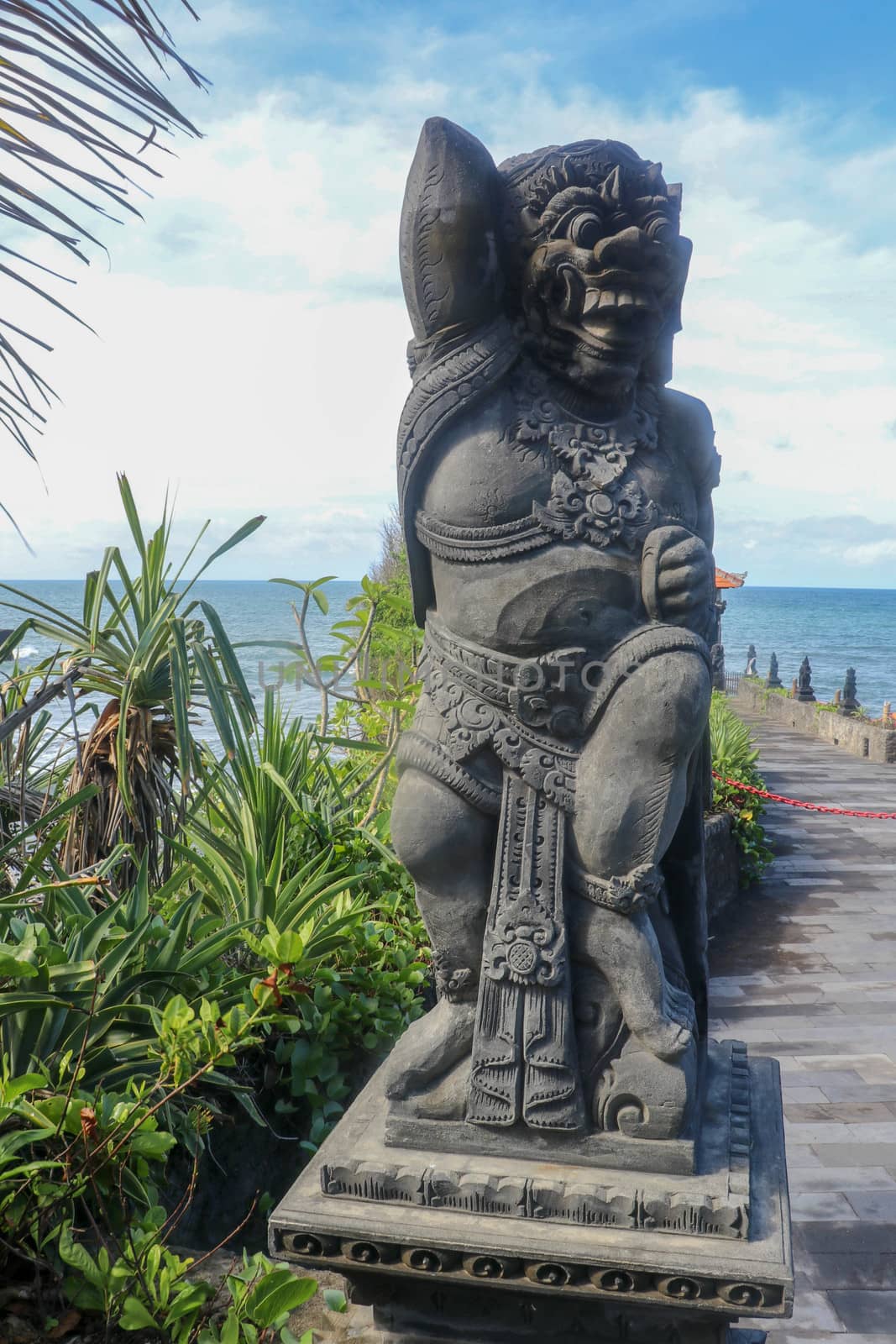 Closeup of stone statue in Temple Batu Bolong near to Tanah Lot in Bali, Indonesia. A carved statue with fine details that stands outside the entrance to Hindu temple as a guardian. Balinese culture.