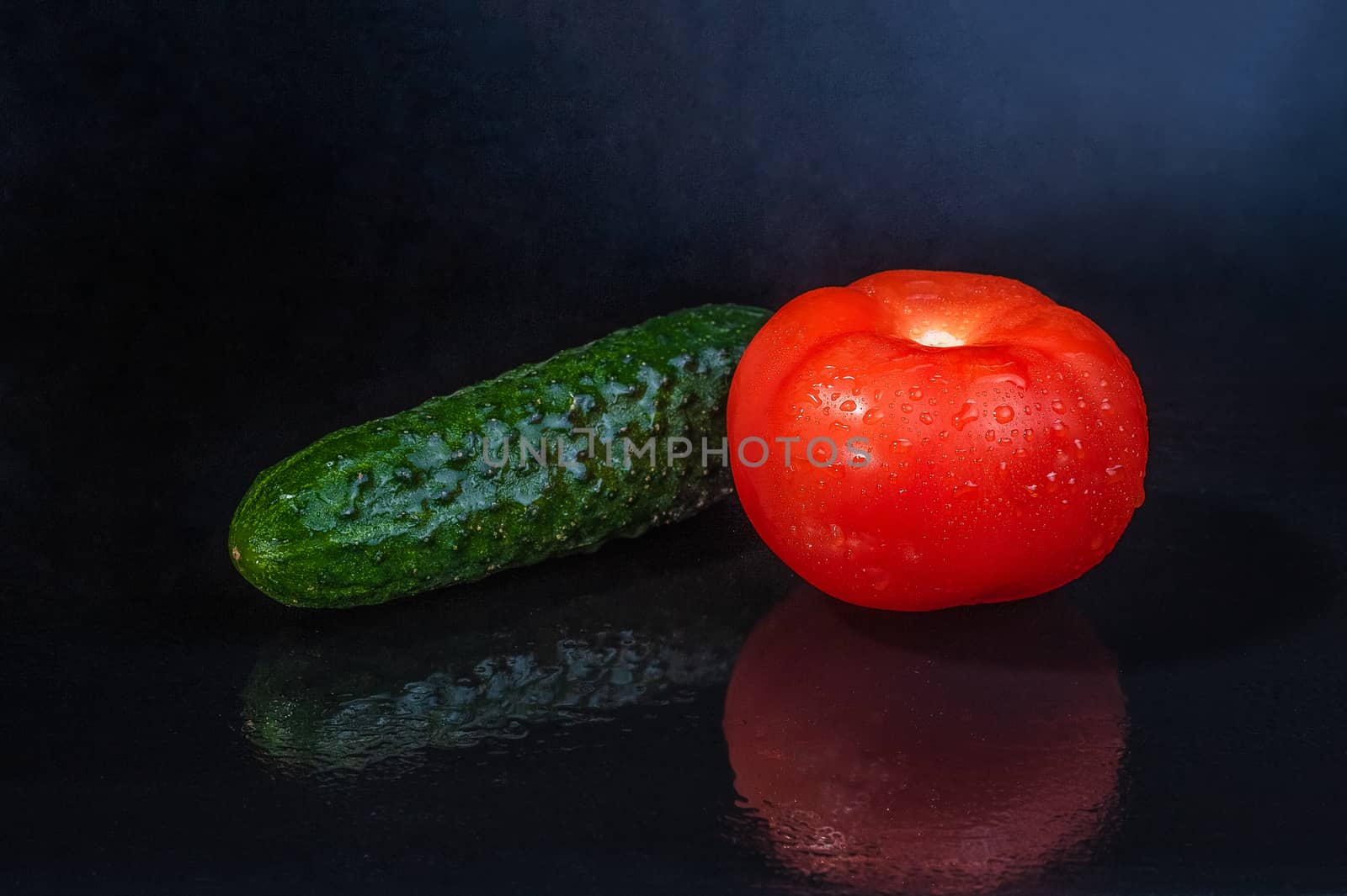 fresh vegetables - green cucumber and red tomato on an isolated black background with reflection by chernobrovin