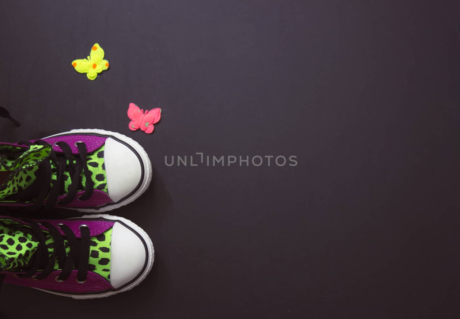 Violet sneakers with leopard print, on black board, vintage filter; copy space