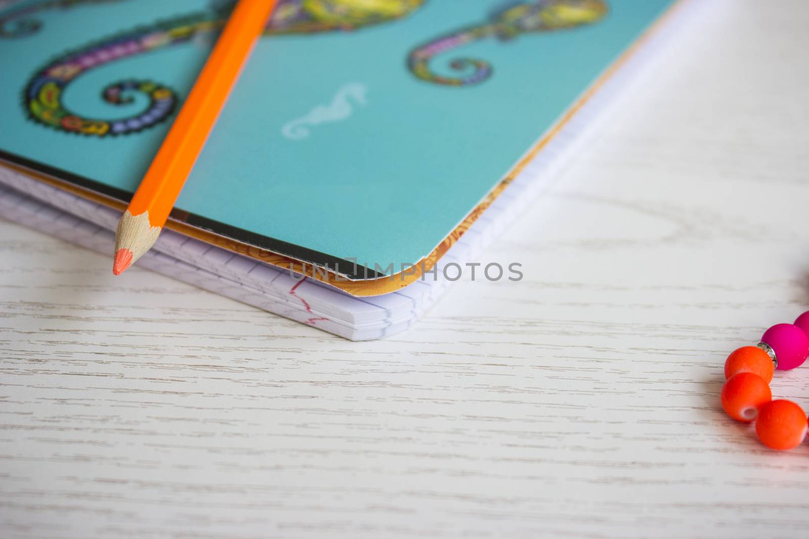 Small blue notebook and orange pencil on white table; shallow depth of field