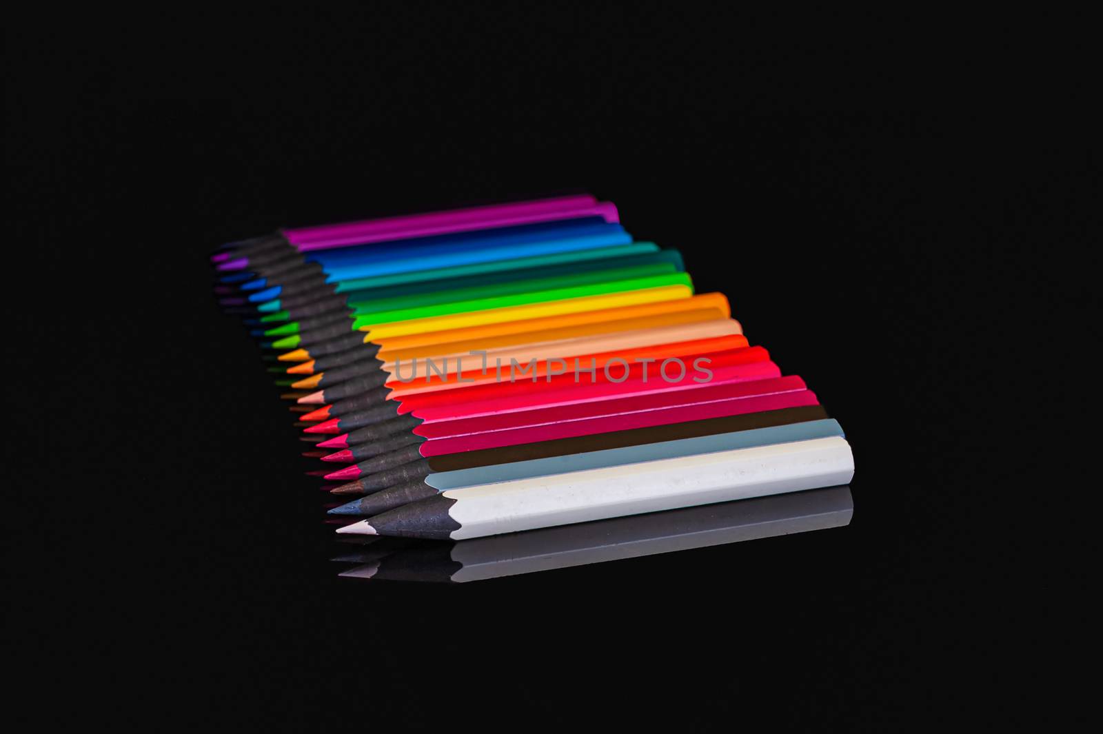 many colored pencils of different colors on an isolated black background with reflection