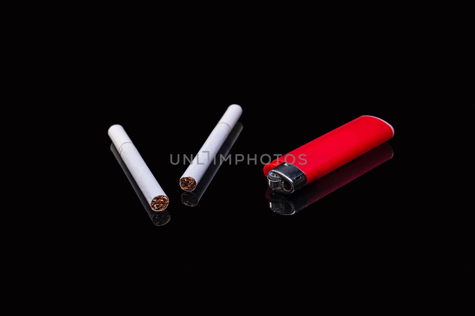 two white filter cigarettes and a plastic gas red lighter on an isolated black background with reflection