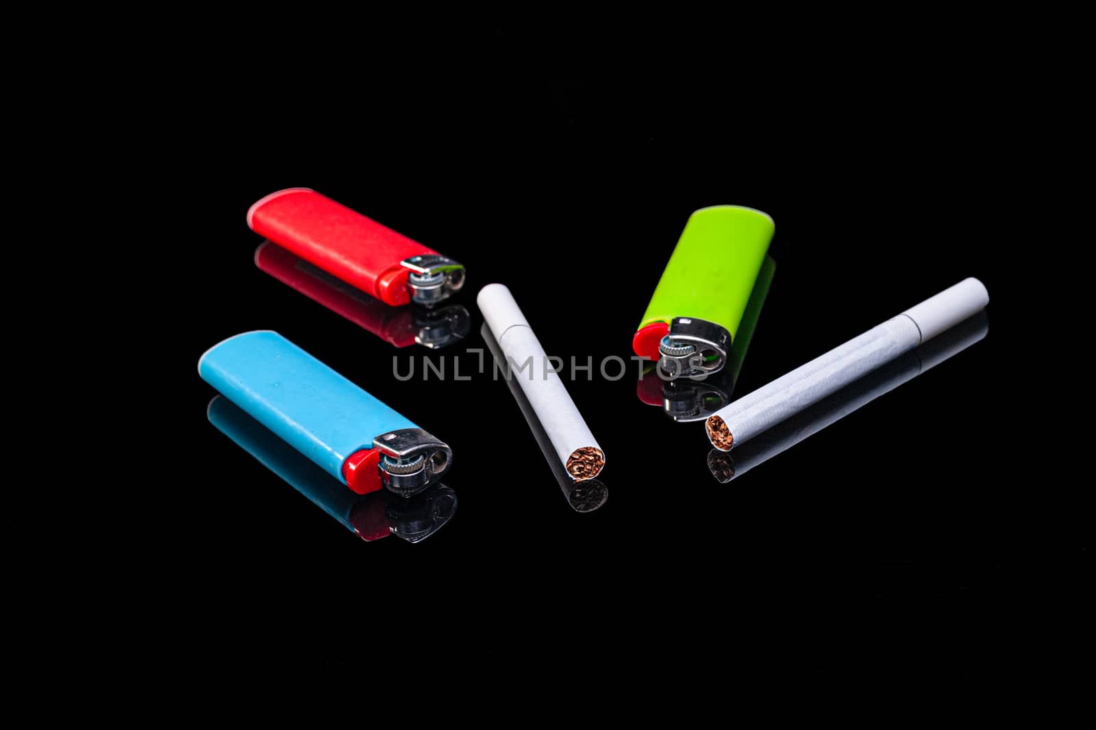white filter cigarettes and plastic gas lighters of different colors on an isolated black background with reflection