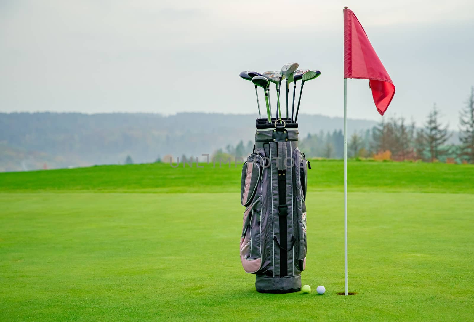 bag with golf equipment on green pitch.