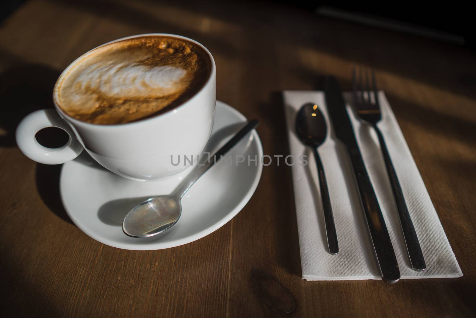 A cup of cappuccino coffee on a wooden table in a cafe setting