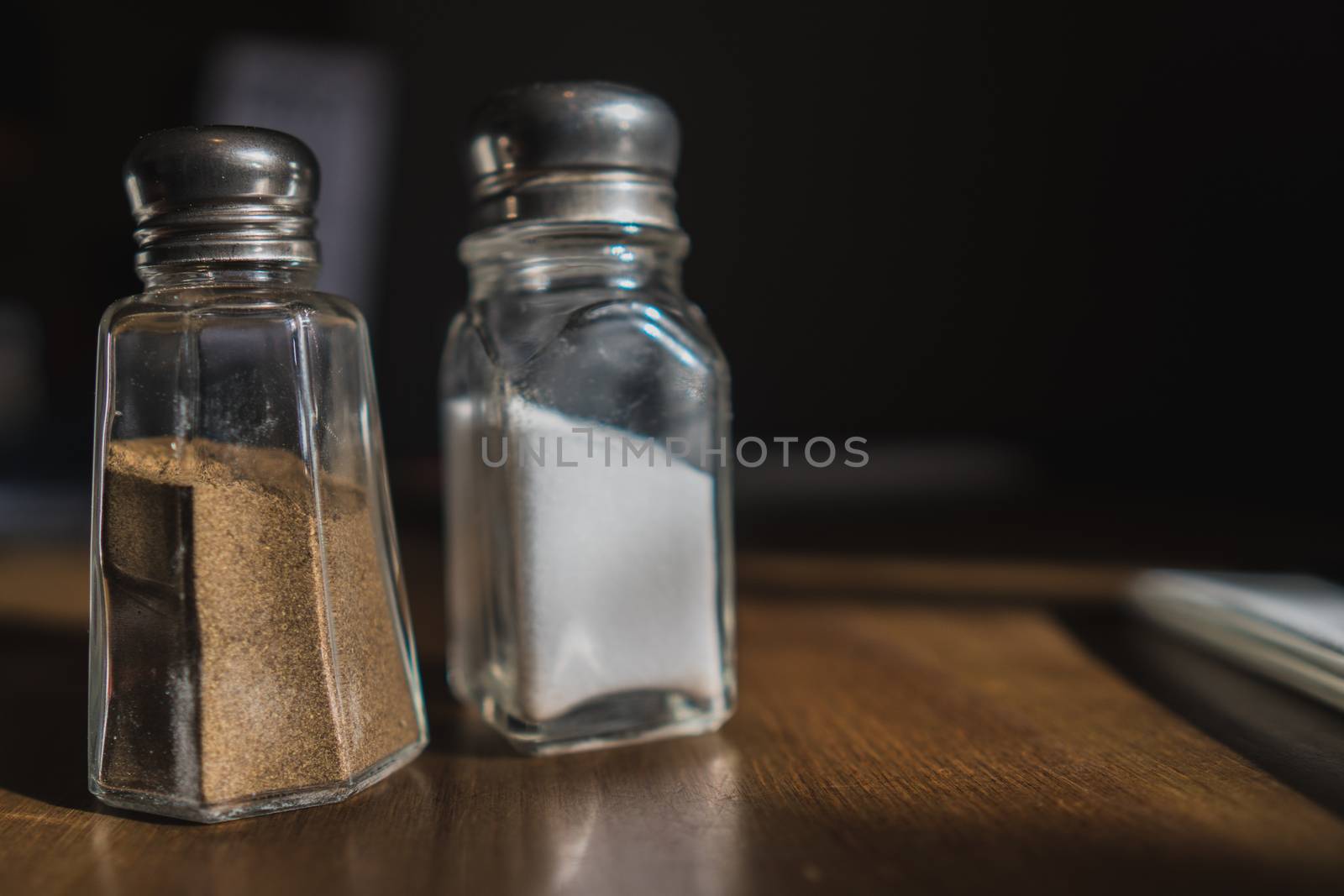 A salt and pepper container on a wooden table in a cafe