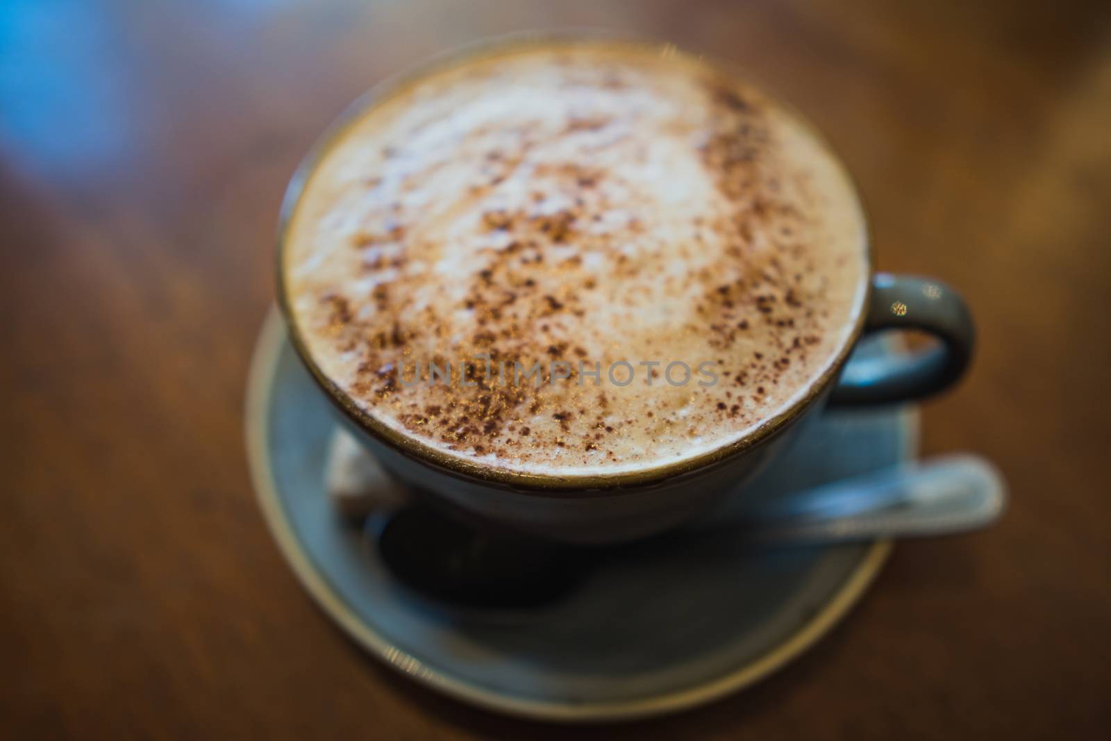 A cup of cappuccino coffee on a wooden table in a cafe setting