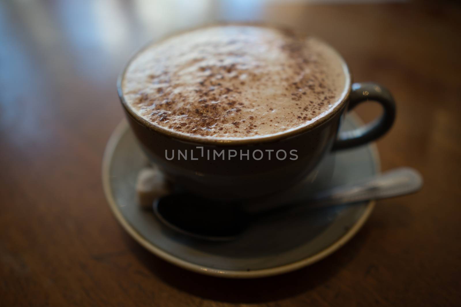 A cup of cappuccino coffee on a wooden table in a cafe setting