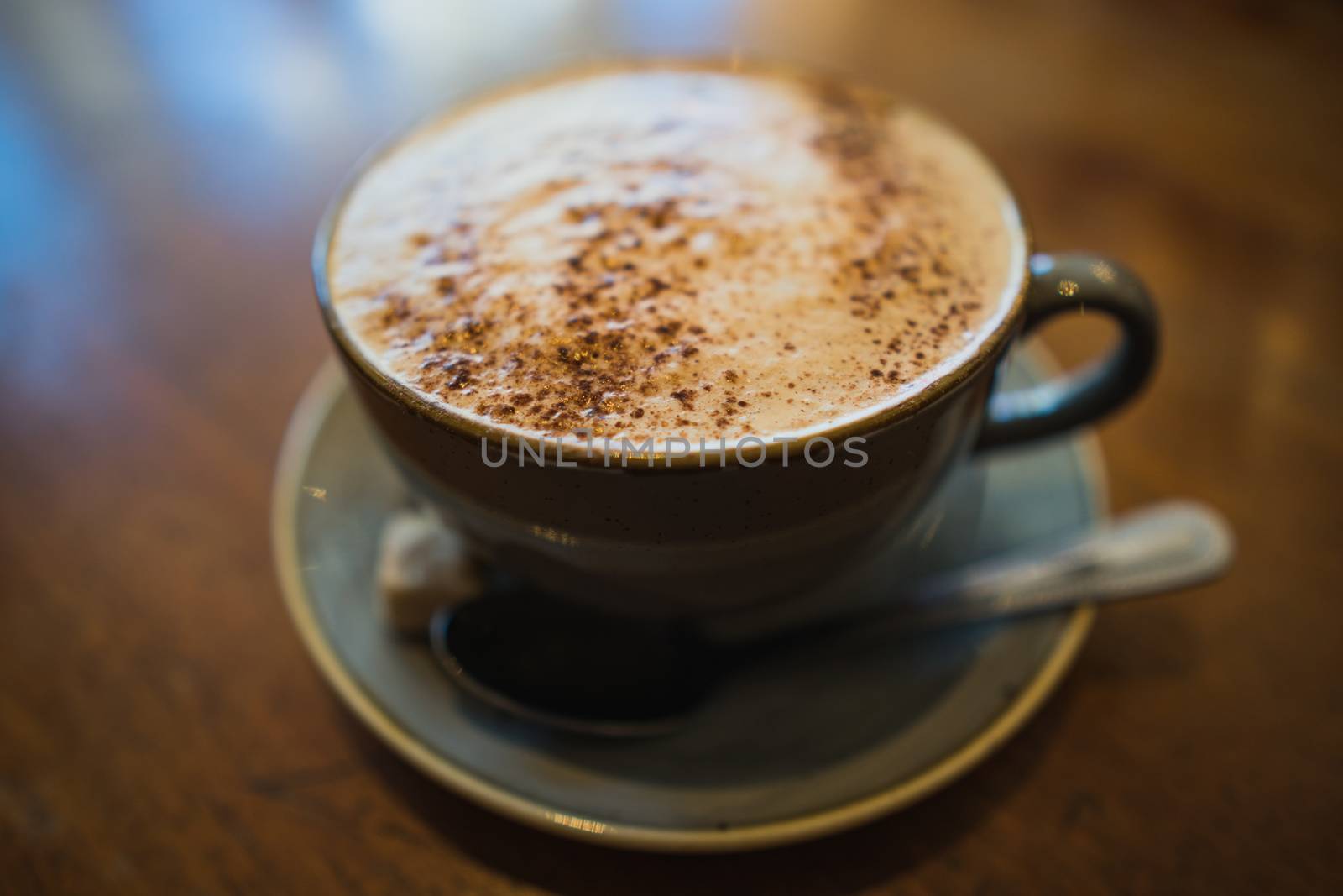 A cup of cappuccino coffee on a wooden table in a cafe setting