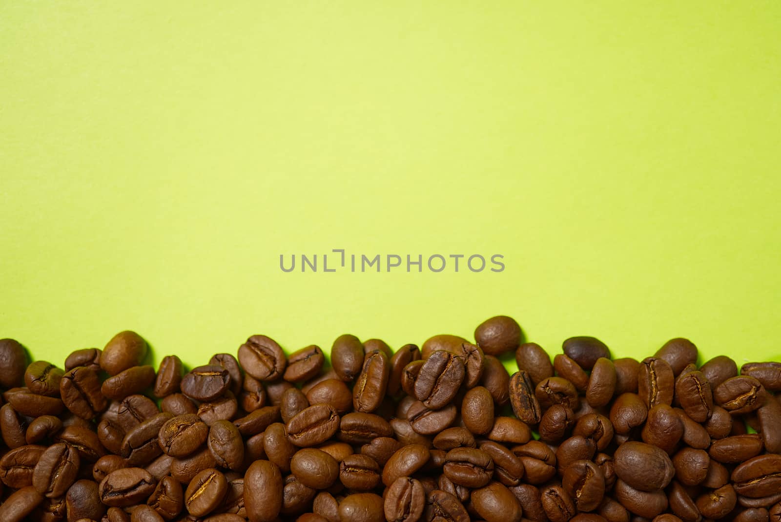 Texture of coffee beans. Roasted coffee beans background. close up Coffee beans with copy space on green background by PhotoTime