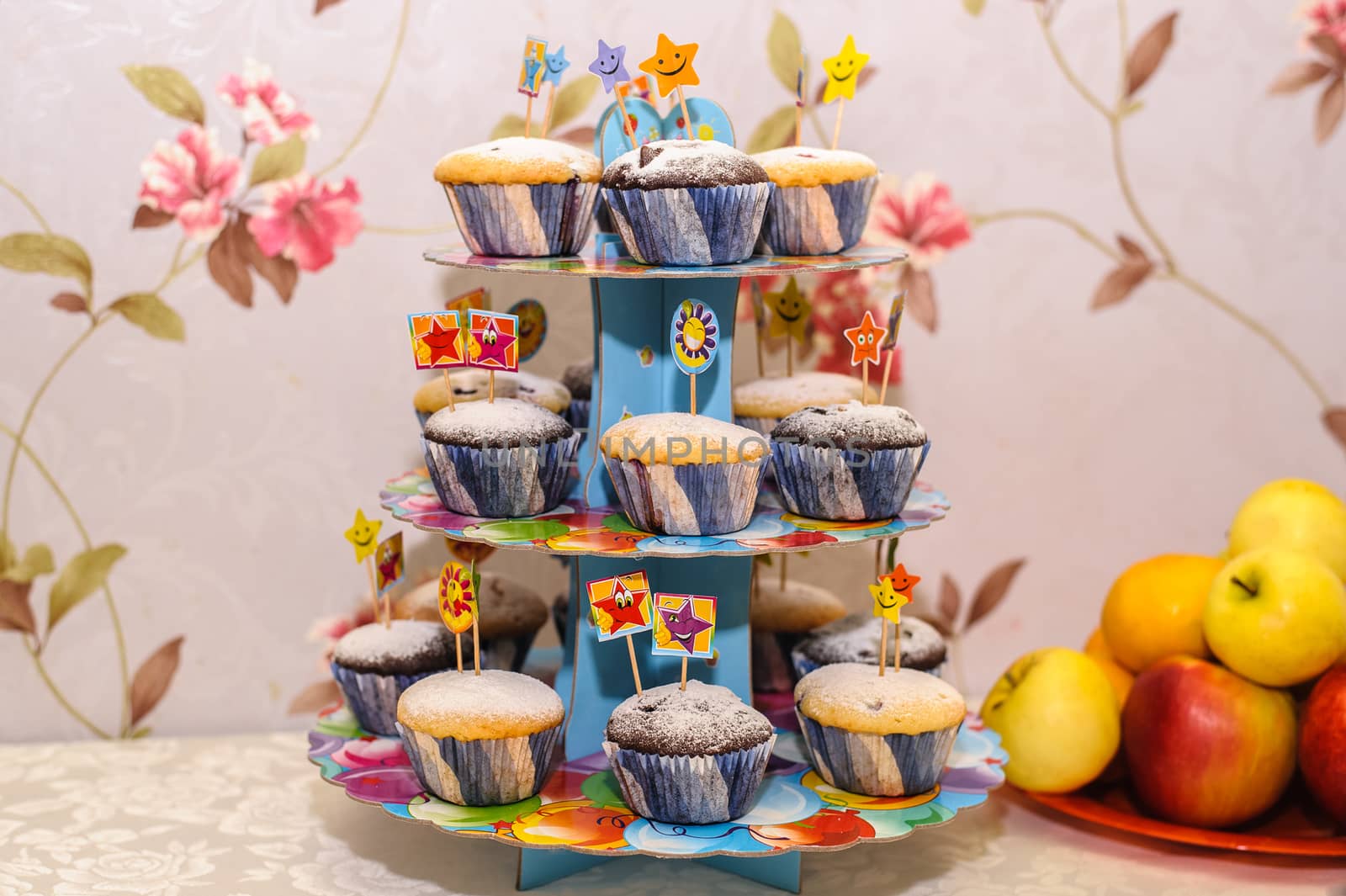 holiday cupcakes with funny flags and a plate with apples on the table