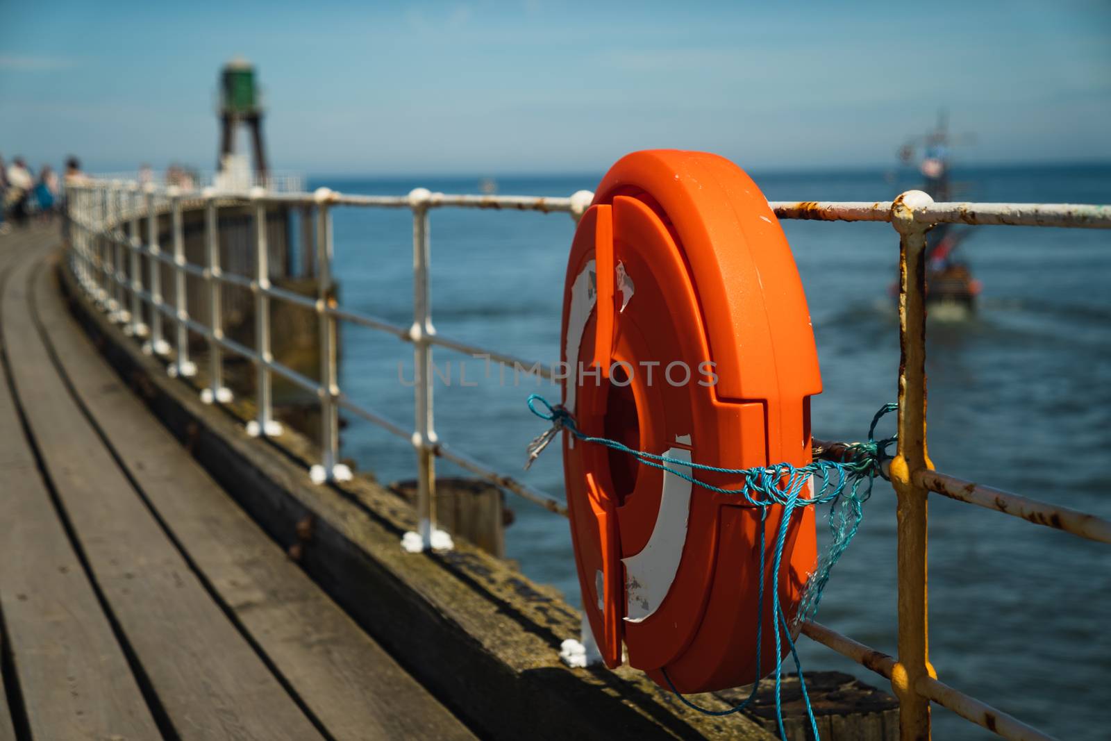 The pier in Whitby in North Yorkshire, England with an orange lifebuoy ring in the foreground