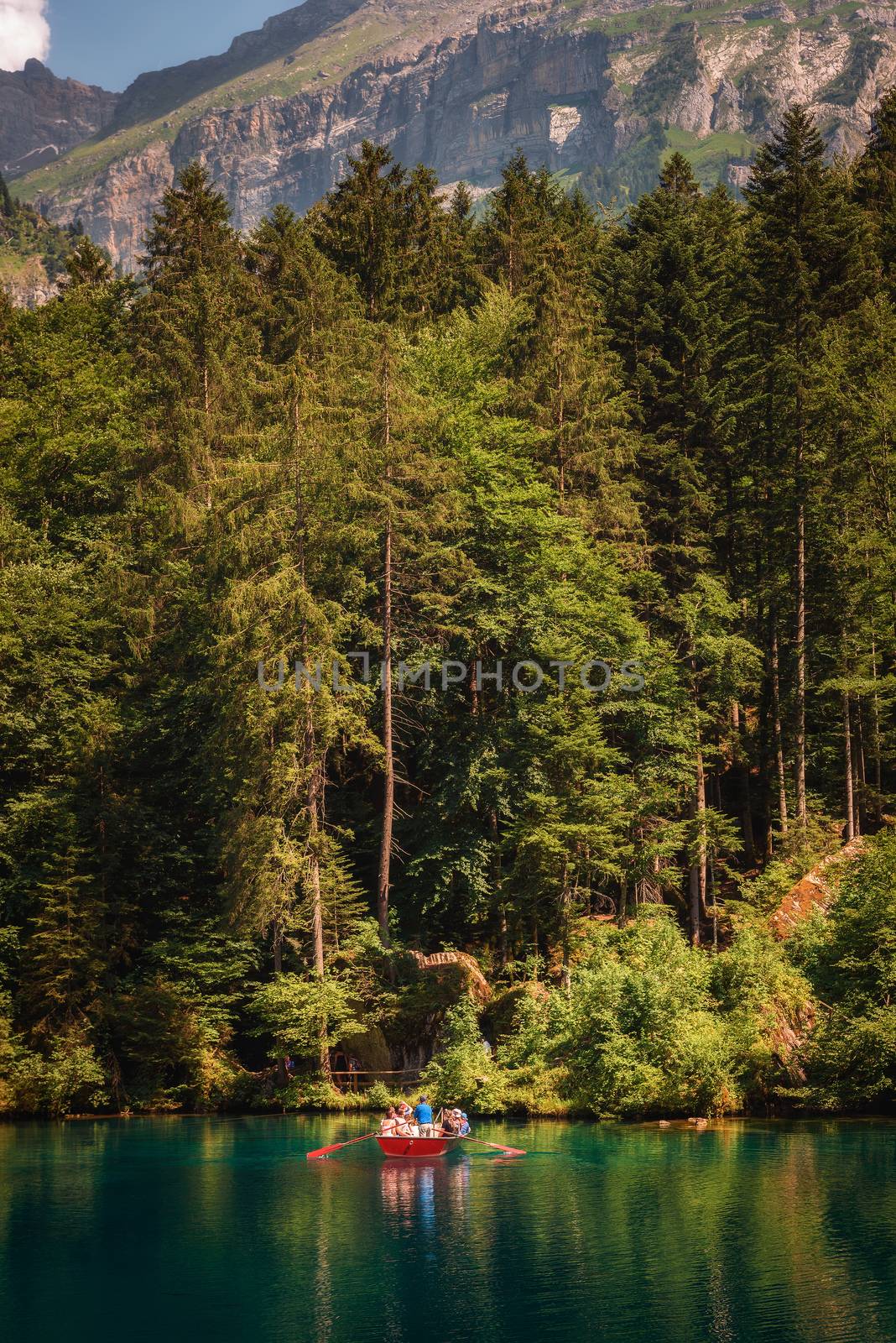 Blausee Lake, Switzerland - July 23, 2019 : Tourists taking a boat trip on Blausee Lake located in the Kander valley above Kandergrund.
