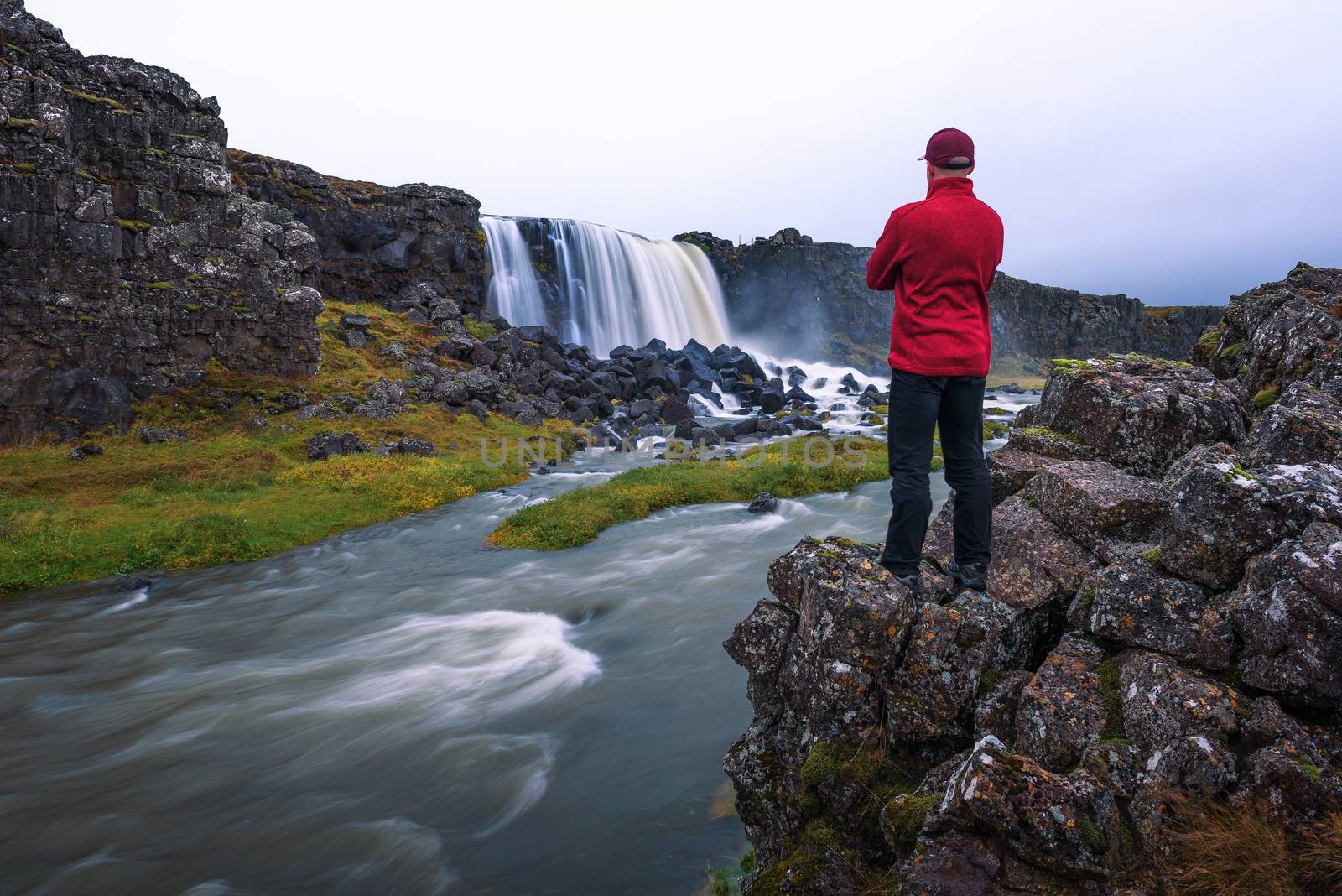 Tourist looking at the Oxarafoss waterfall in Iceland. This waterfall is located in the Thingvellir National Park on the river Oxara.