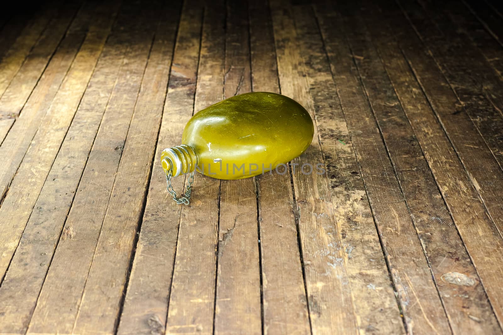 an old military canteen bottle from World War II lies on a shabby wooden floor by chernobrovin