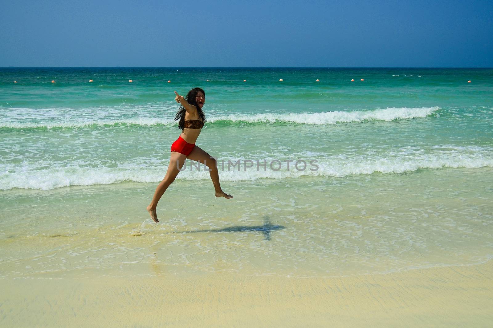 happy sexy young girl jumping on the beach by the sea.