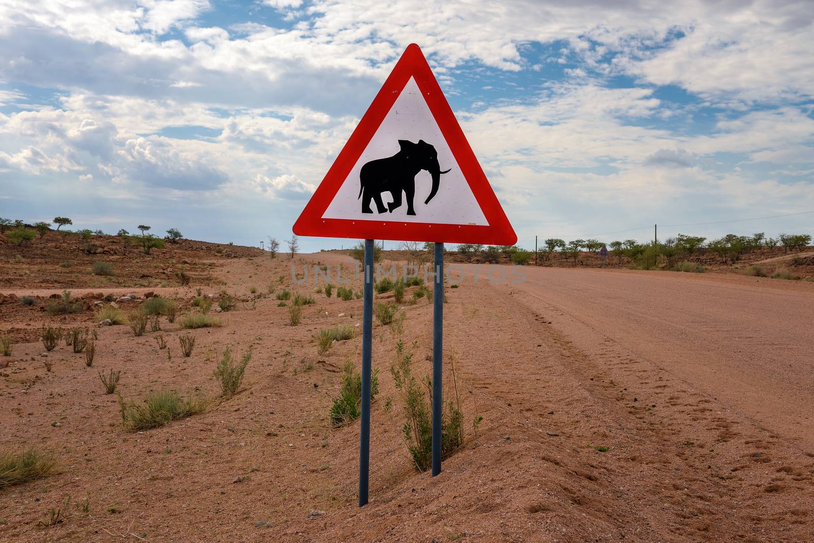 Elephant crossing warning road sign placed by a gravel road in the desert of Namibia.