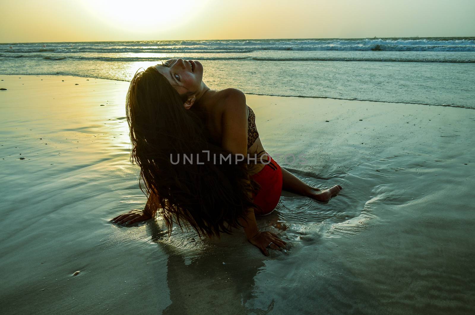 beautiful girl sitting on the beach at sunset