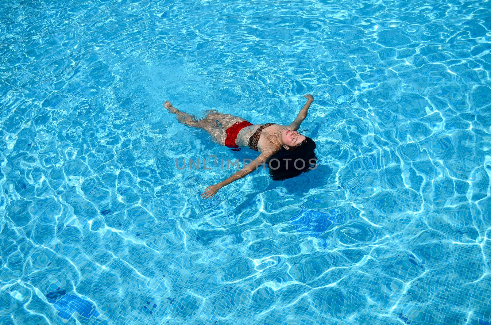 A beautiful girl is swimming in the pool in sunny day by chernobrovin