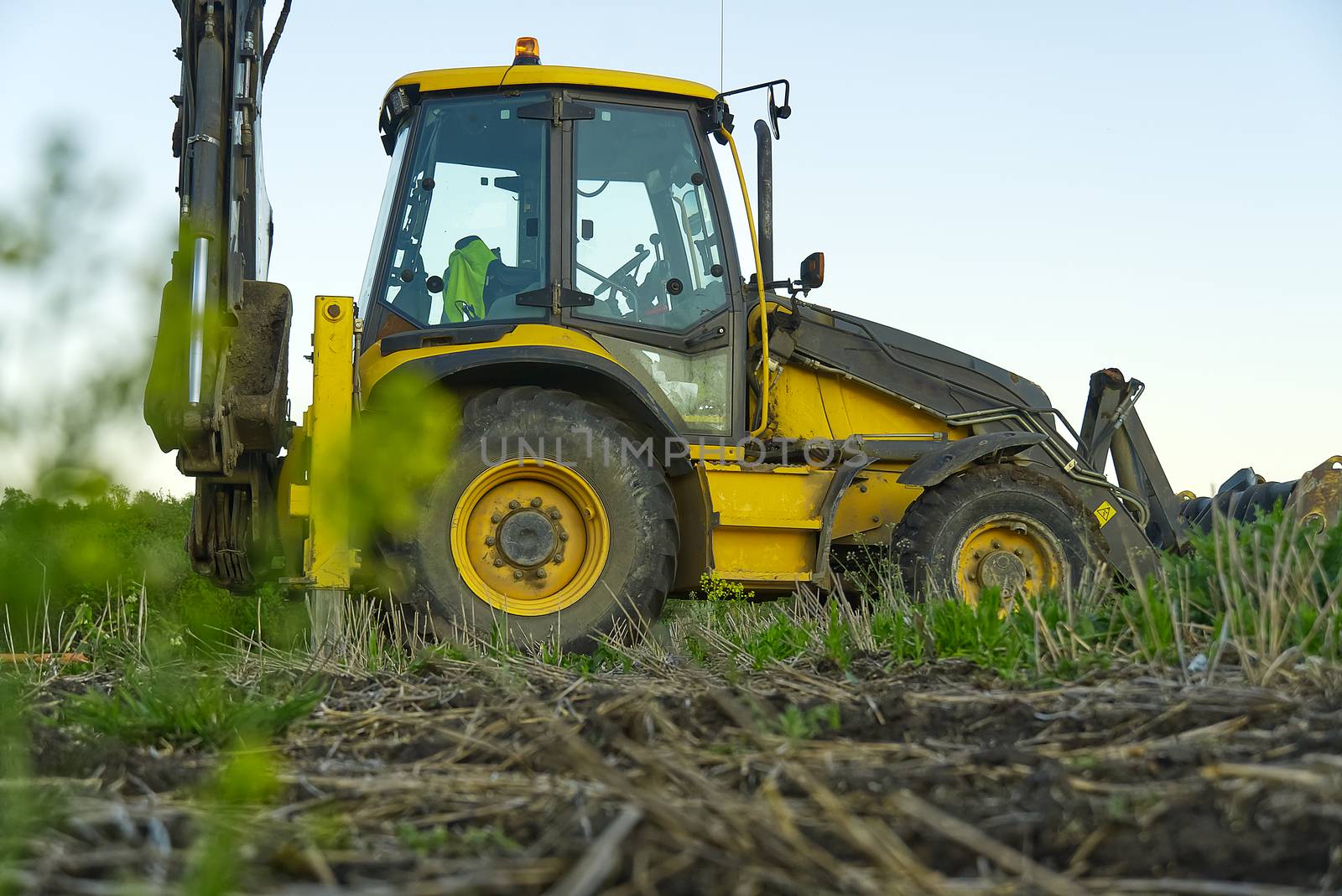 Yellow Excavator. yellow tractor on the field. Construction Machinery On Field. large yellow wheel loader aligns a piece of land for a new building. Tractor On Farmland. by PhotoTime