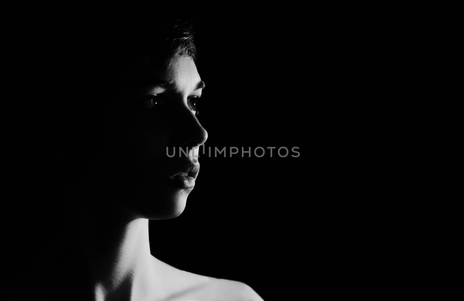 Intense BW backlit studio portrait of young woman on black background