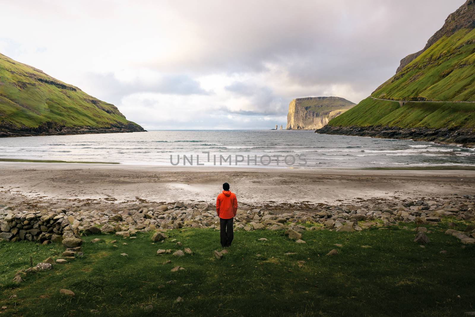 Tourist standing at the beach in Tjornuvik located on the coast of a beautiful bay in the Faroe Islands, Denmark.