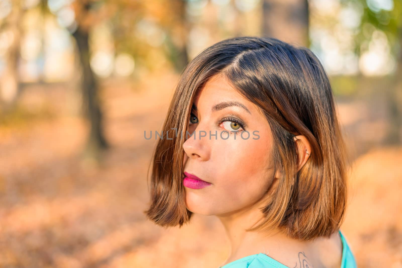 face of a beautiful young black-haired woman half-covered by hair in a yellow autumn forest