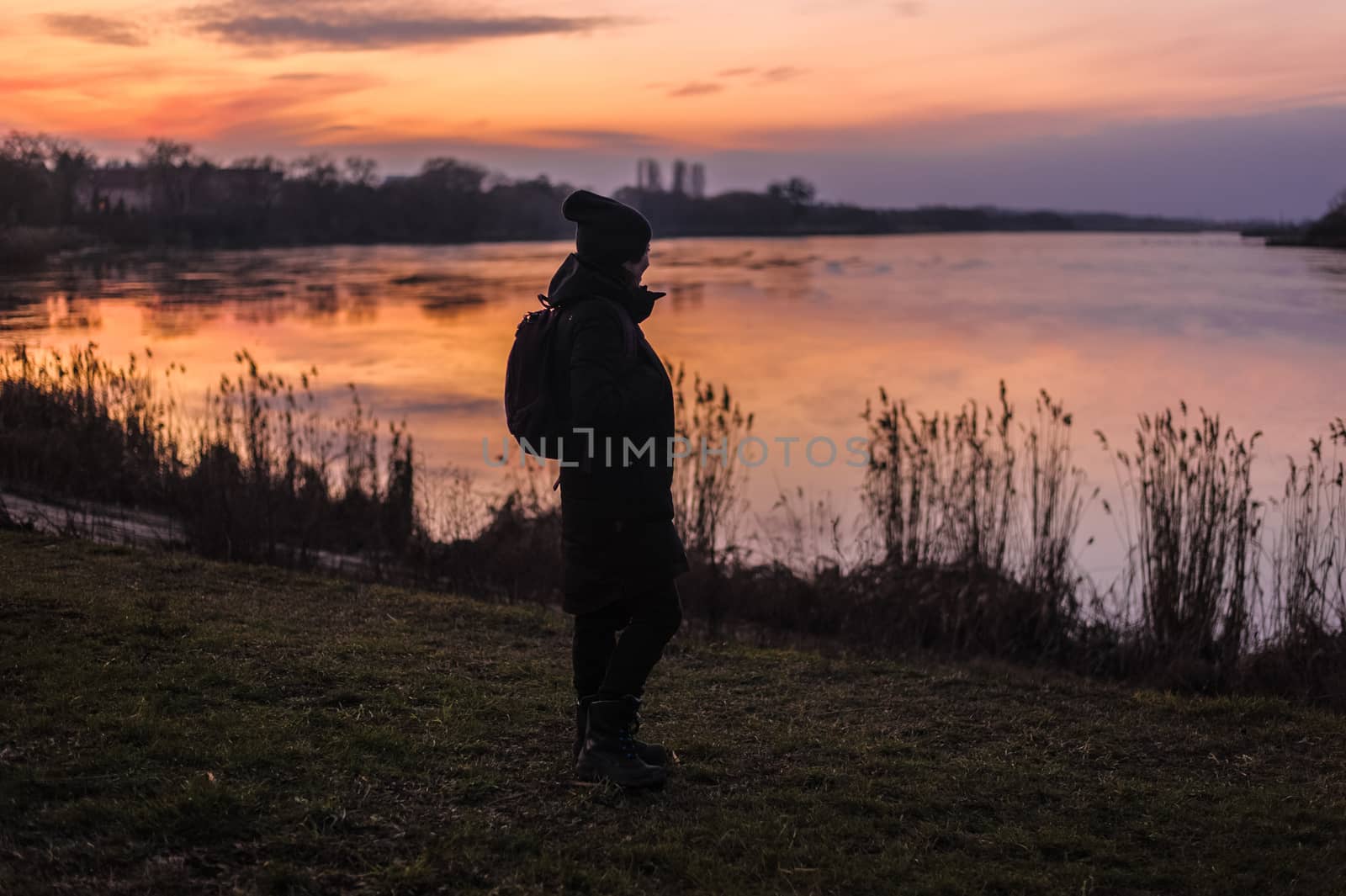 silhouette of a human on the background of a lake in the forest looking at a beautiful sunset by chernobrovin