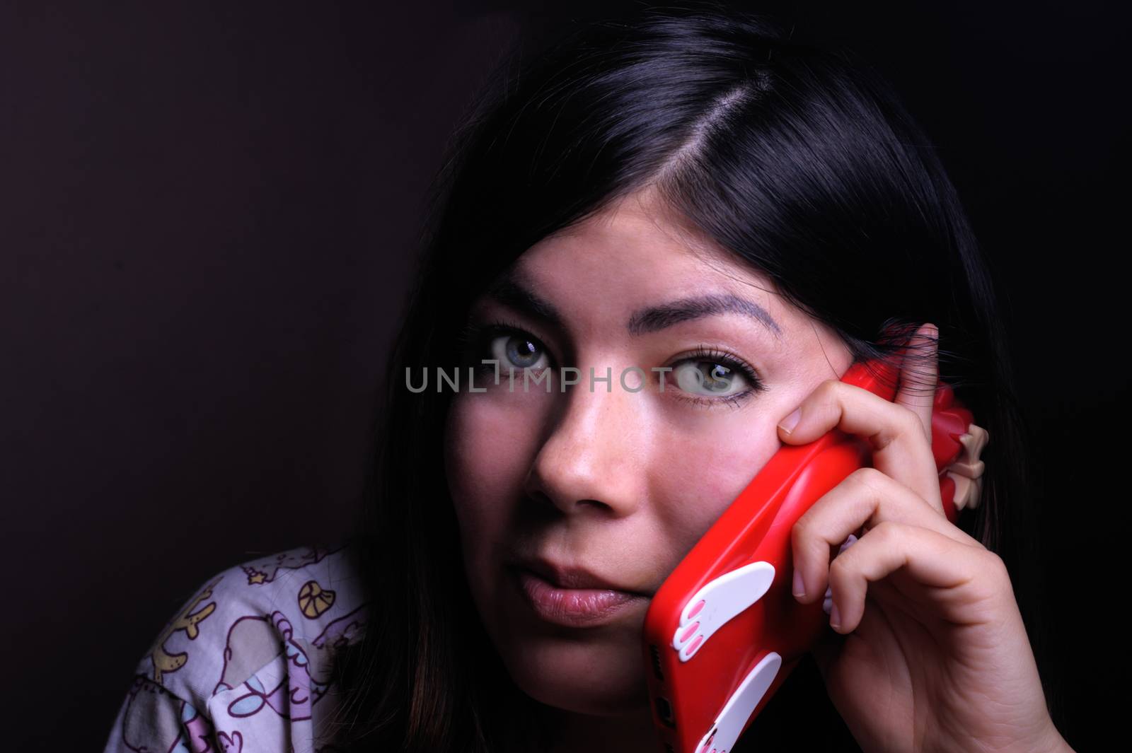 beautiful brunette girl with green eyes talking on a cell phone in a red case