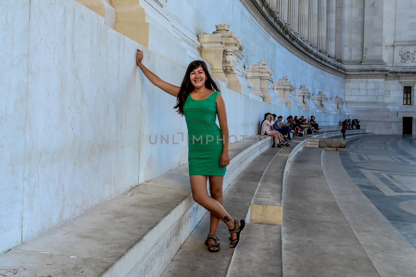 smiling girl in a green dress stands on the marble steps of the Vittorio Emanuele II Monument in Rome, Italy