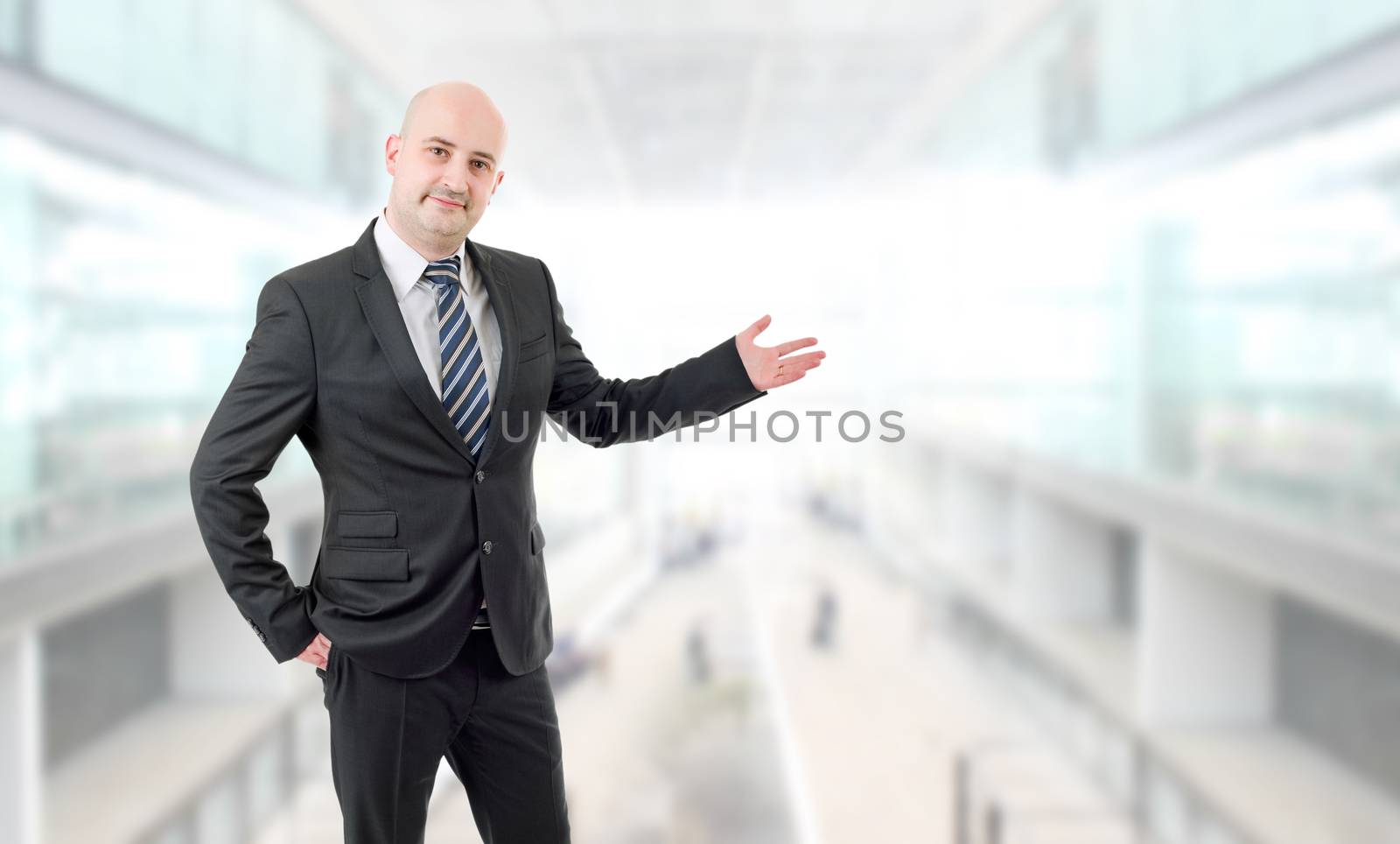 Handsome businessman with arm out in a welcoming gesture, at the office