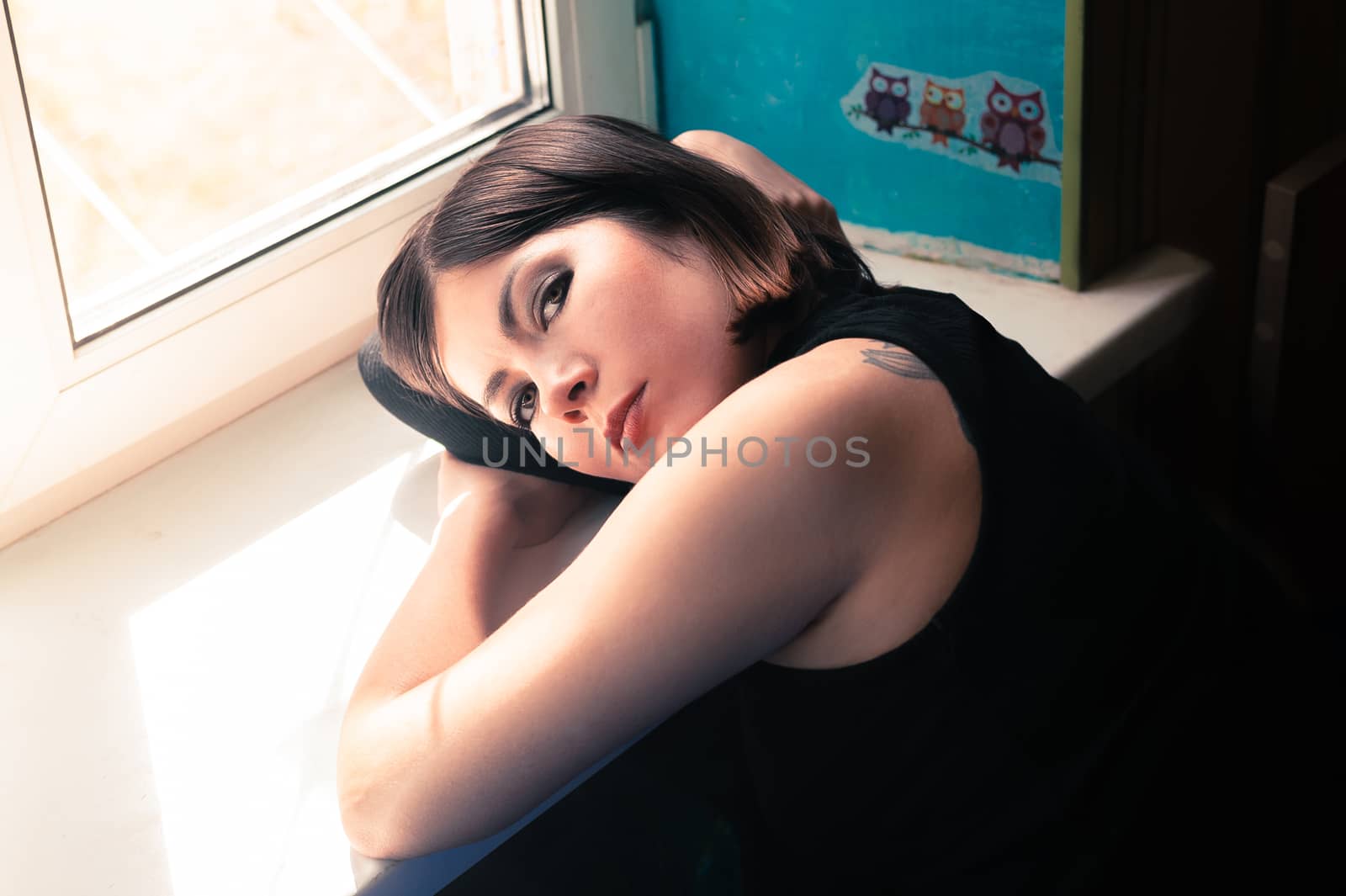 nice brunette girl in black clothes lies on a windowsill near the window