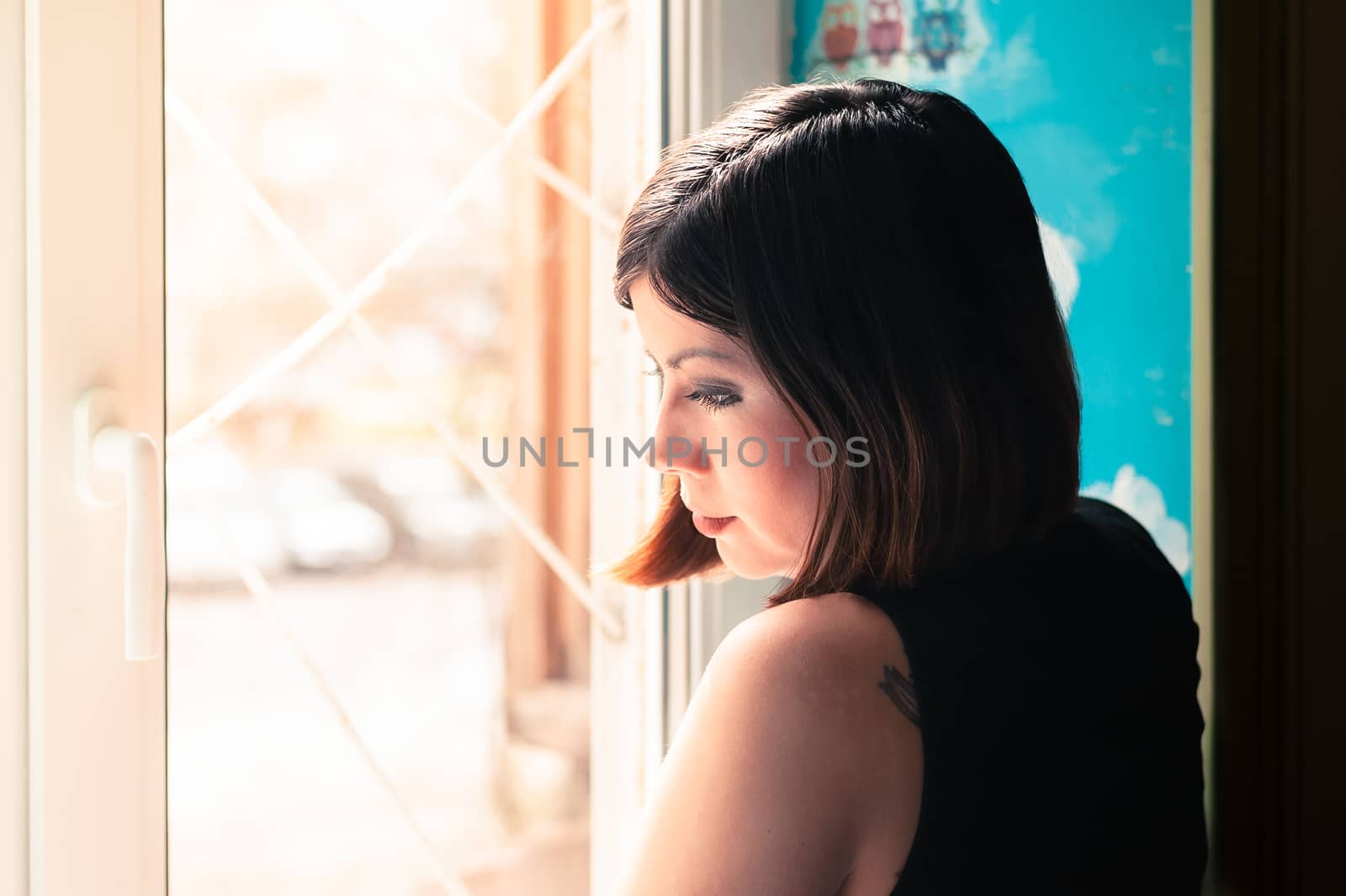 beautiful young brunette woman stands thoughtfully at the window
