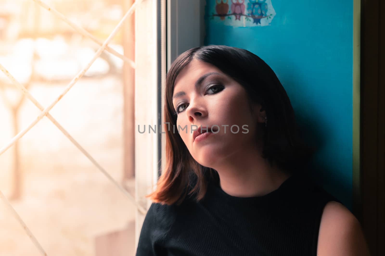 portrait of a very beautiful brunette girl near the window in a sunny day