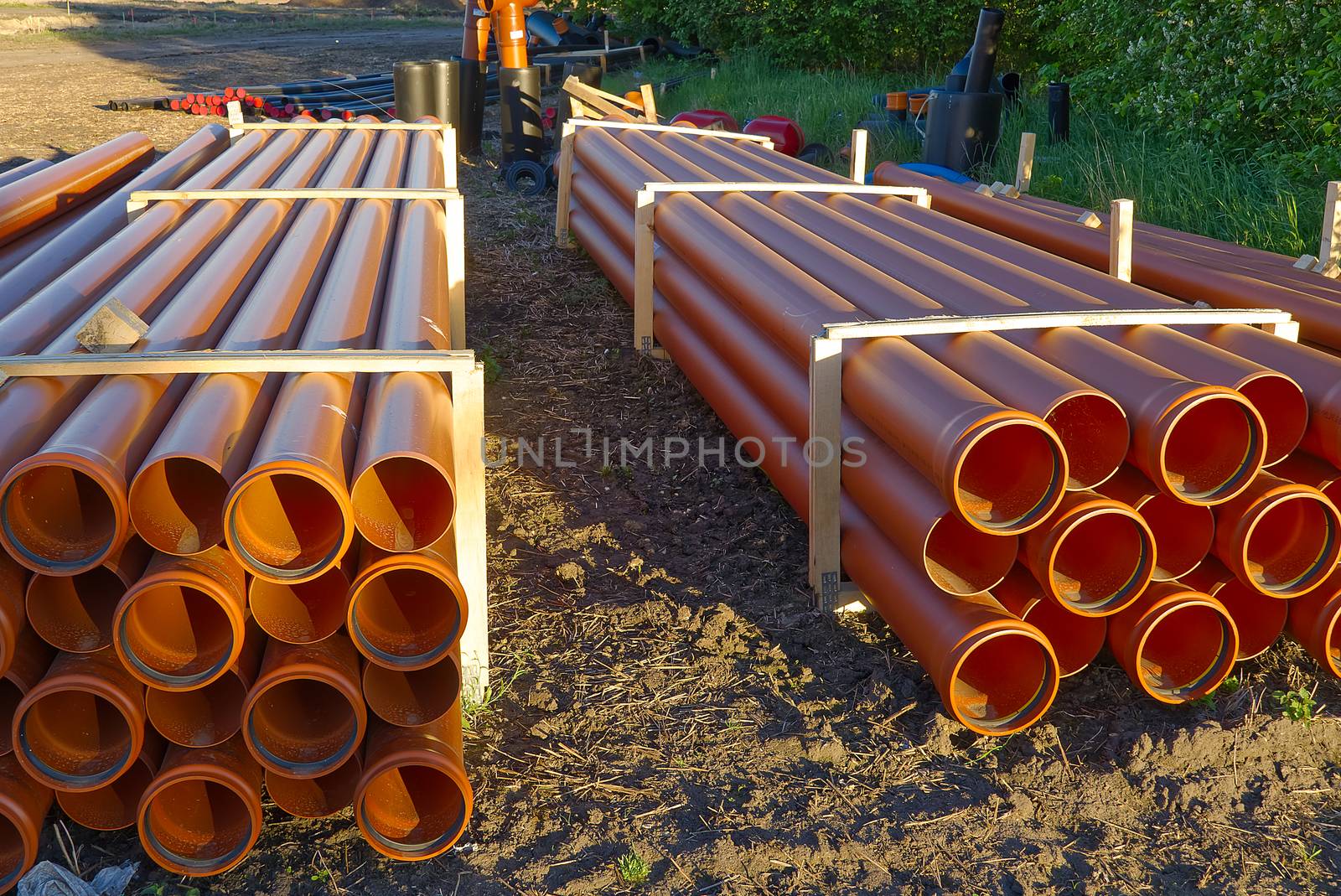 orange sewer pipes at a construction site. Underground orange plastic pipes. Stacked PVC orange pipes. by PhotoTime