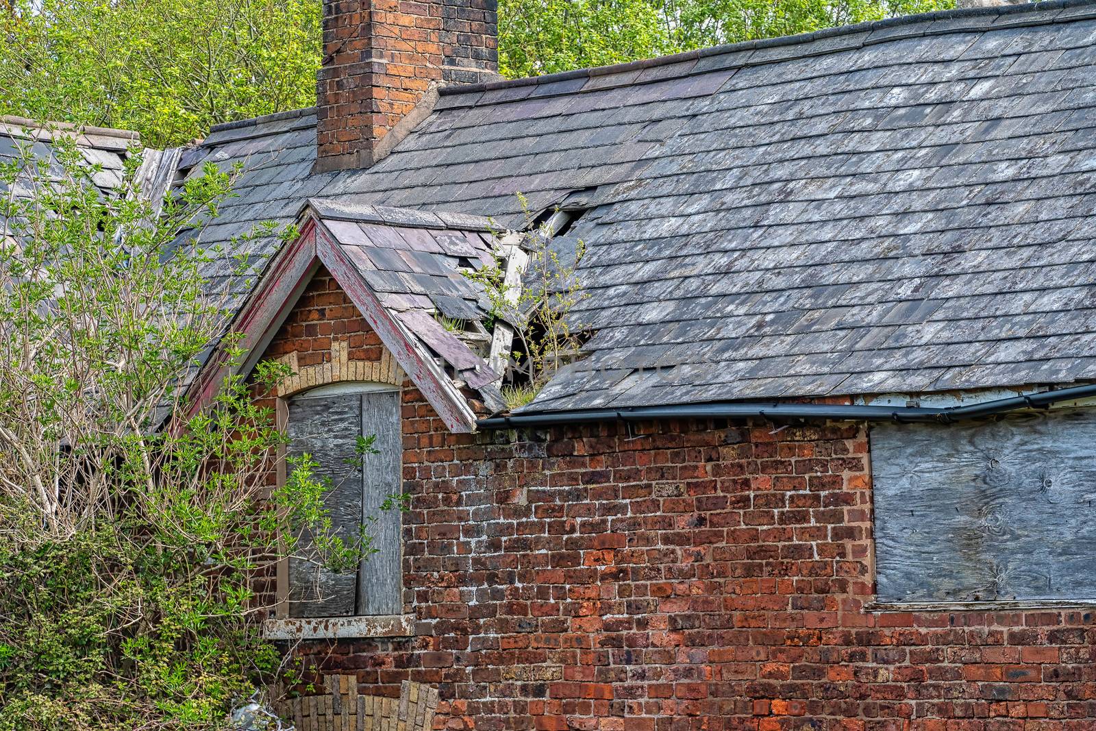 Damaged slate roof tiles on a pitched roof on a derelict house