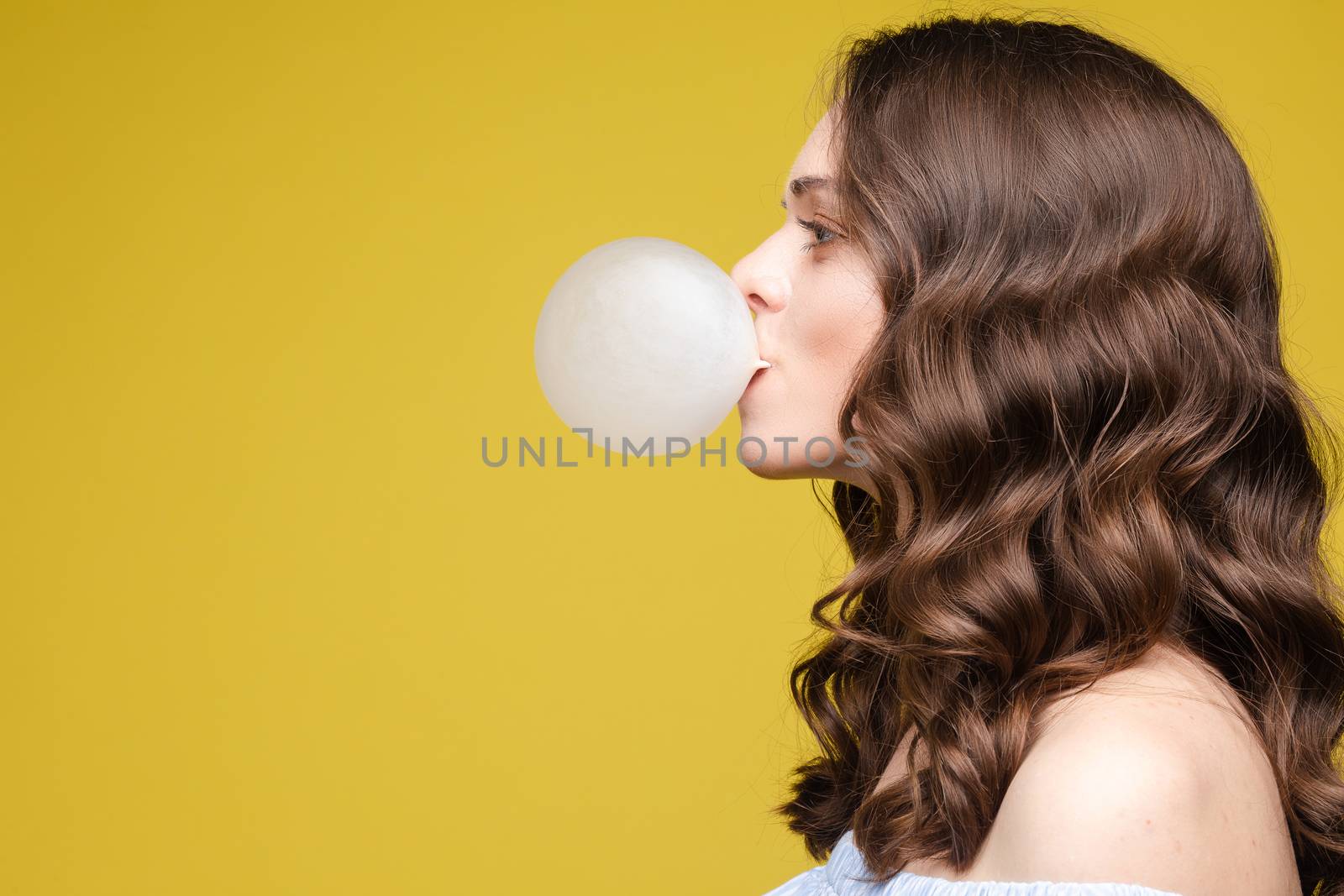 Side view of beautiful girl blows a sphere from chewing gum by StudioLucky
