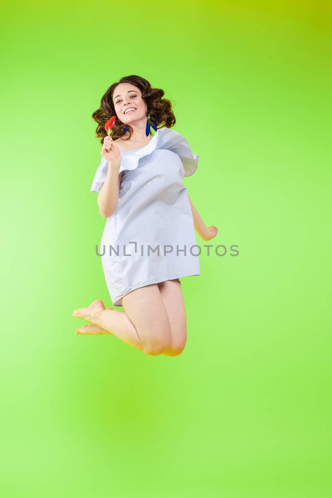 Cheerful brunette young woman in casual outlook jumping in mid air in studio. by StudioLucky