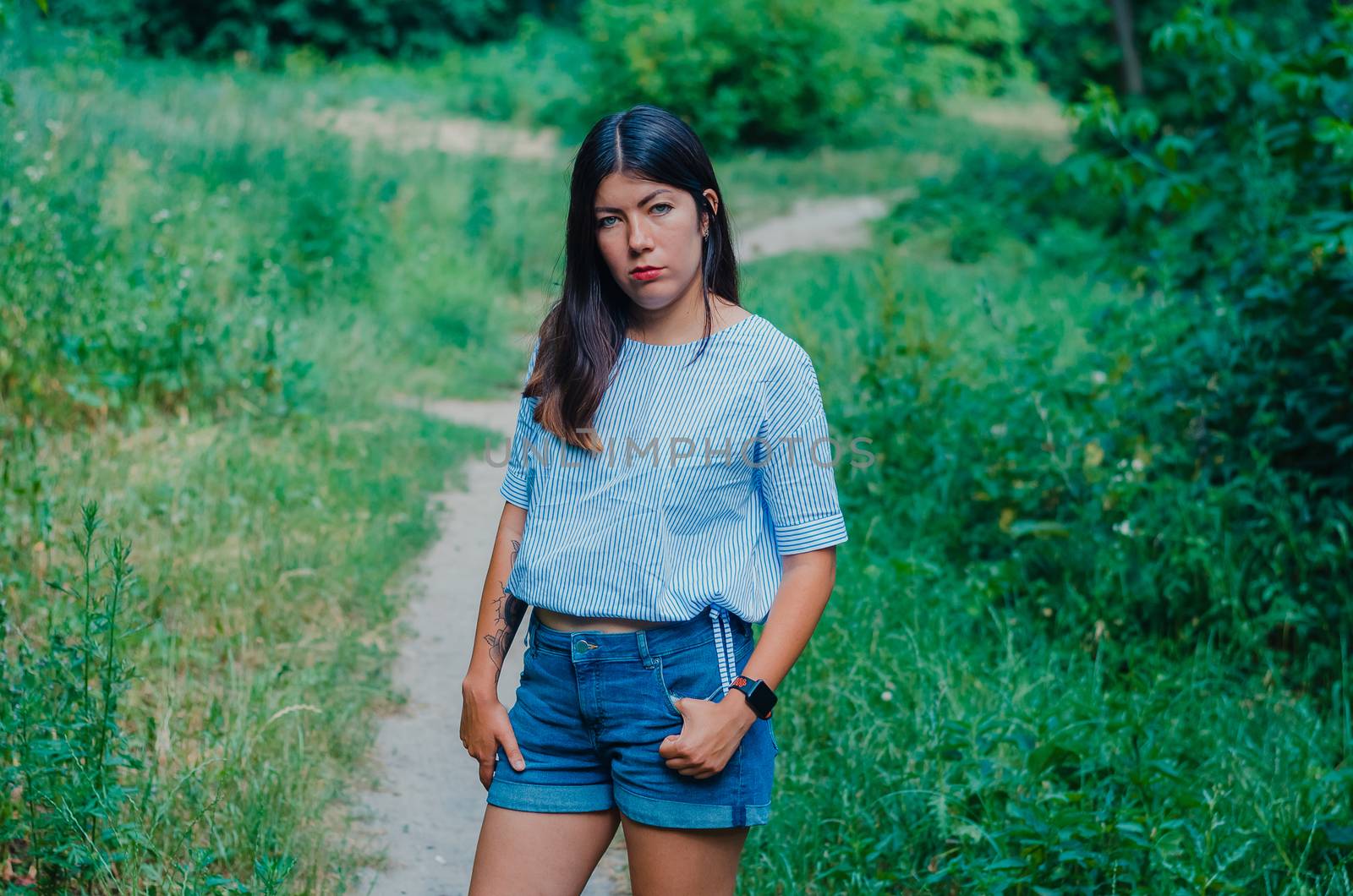 Beautiful young brunette woman in green summer park