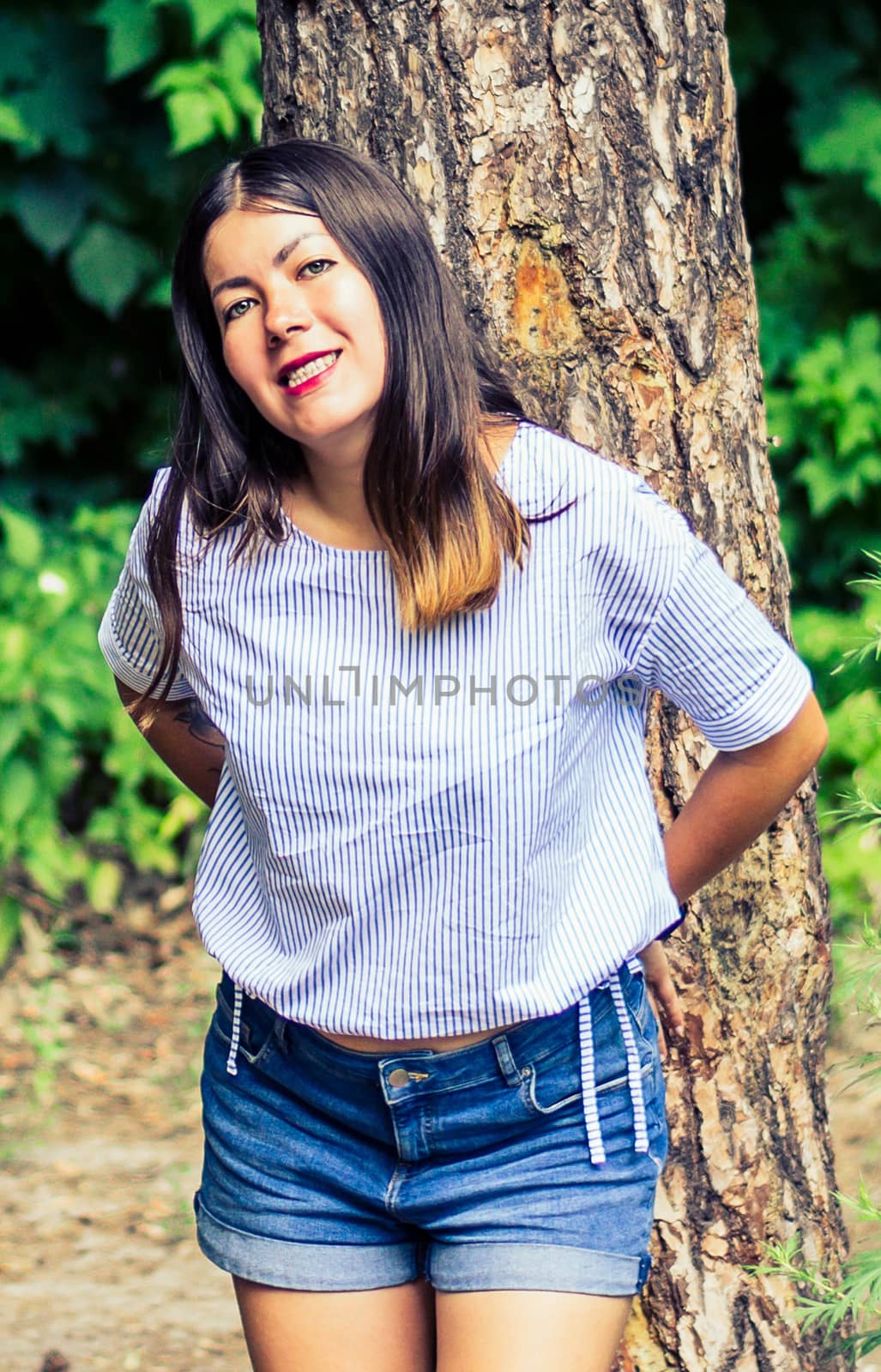 beautiful young brunette woman standing near tree