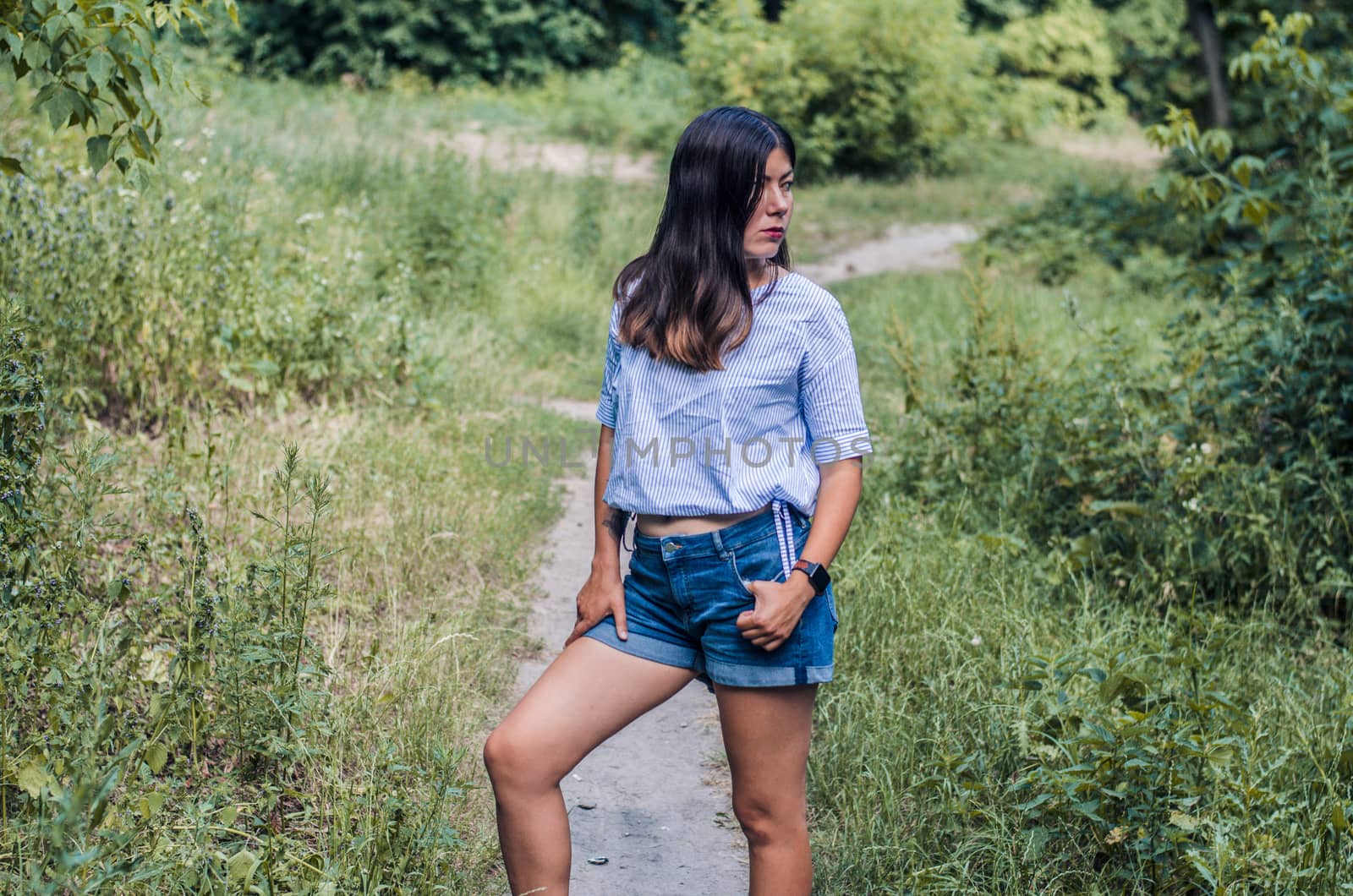 Portrait of happy young Caucasian woman wearing in a white blouse and blue denim shorts by chernobrovin